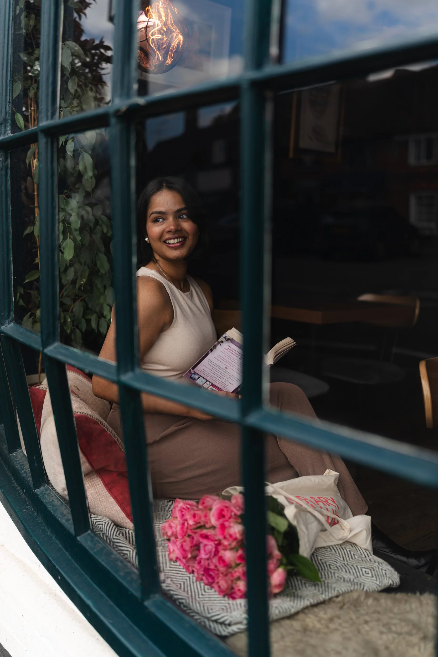 Social media influencer sitting in the window of The Griffin with a coffee and book in Old Amersham, Buckinghamshire during a branding shoot