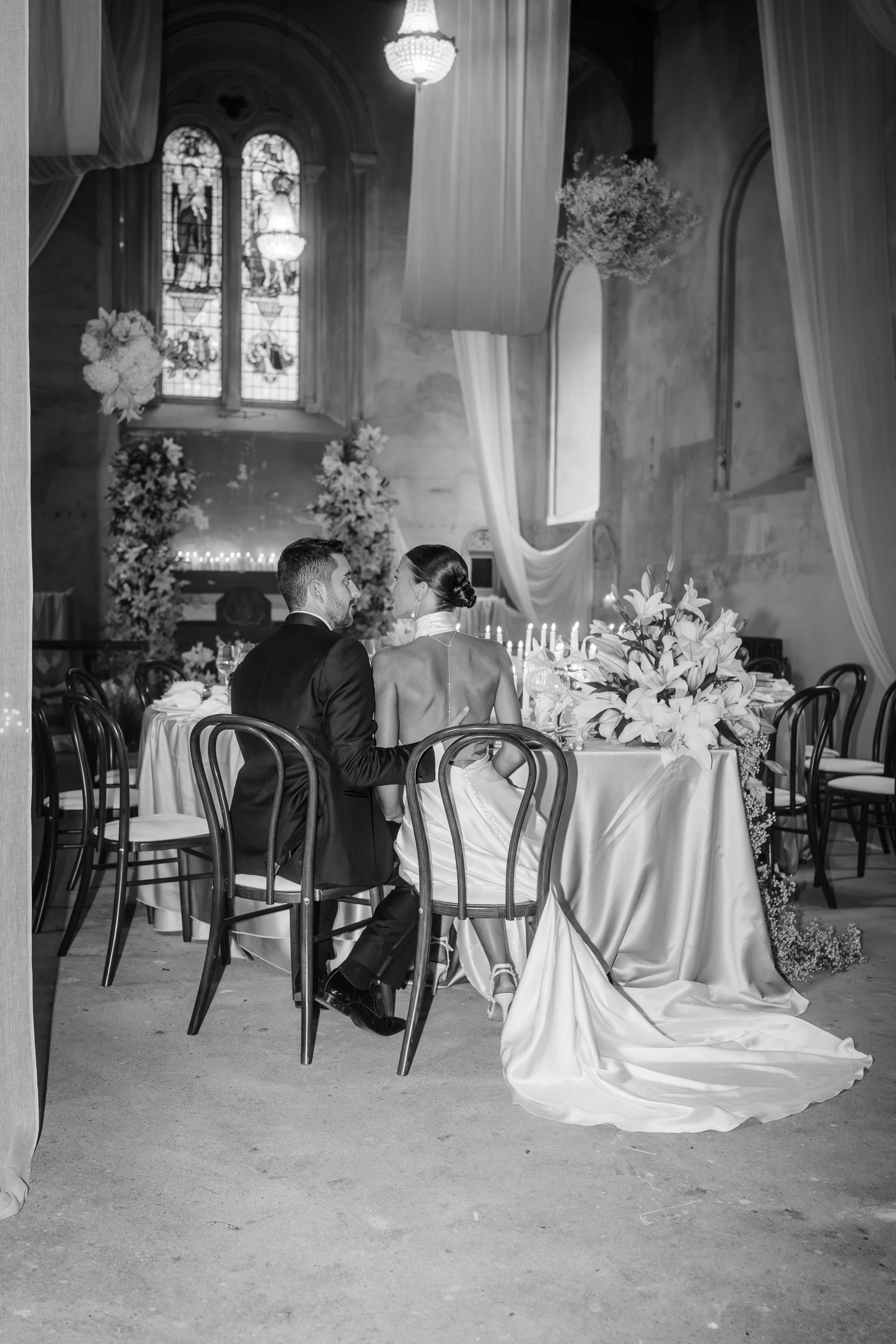 Bride and groom sitting together at the head table in a candlelit wedding reception inside  The Bell Tower at The Elvetham Hotel in Hampshire