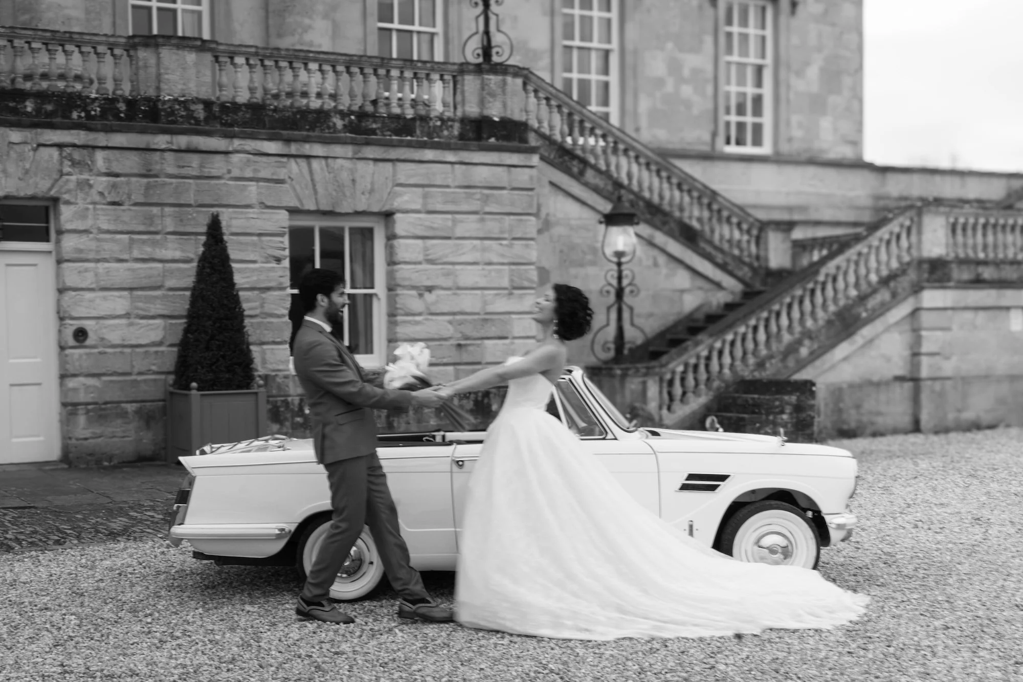 Newlyweds beside a classic wedding car outside Kirtlington Park, an Oxfordshire stately home wedding venue