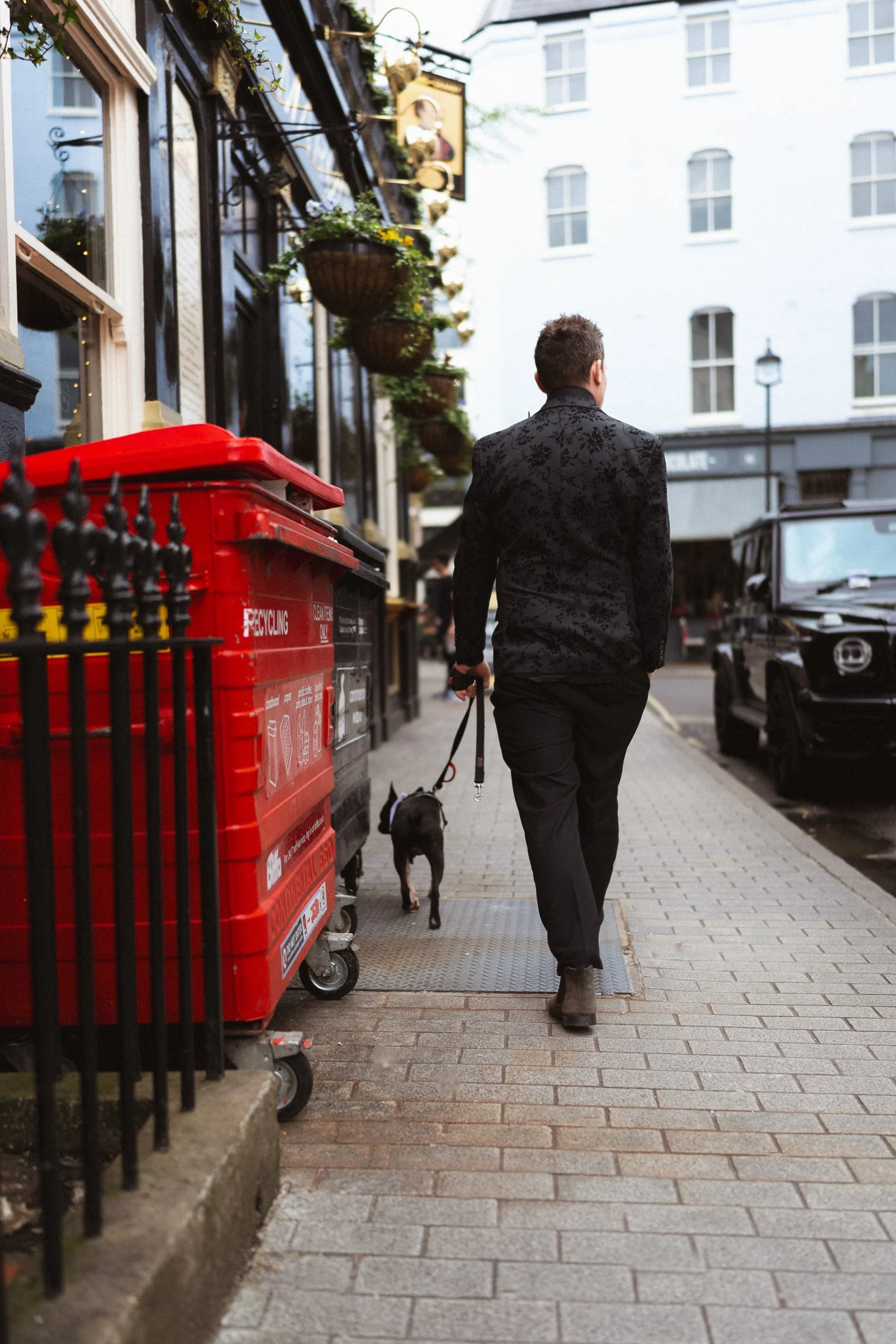 Groom walking his dog to the wedding reception near The Union Club after the Fitzrovia Chapel wedding in London