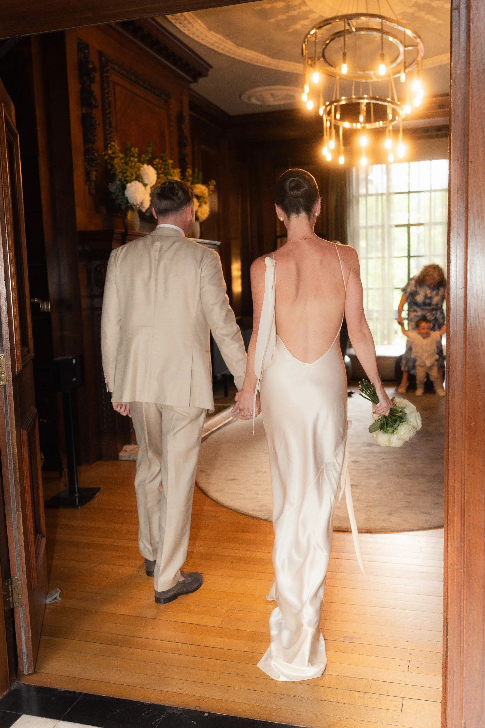 Bride and groom walk into greet their guests at an intimate wedding ceremony at Marylebone Town Hall Registry Office in London  
