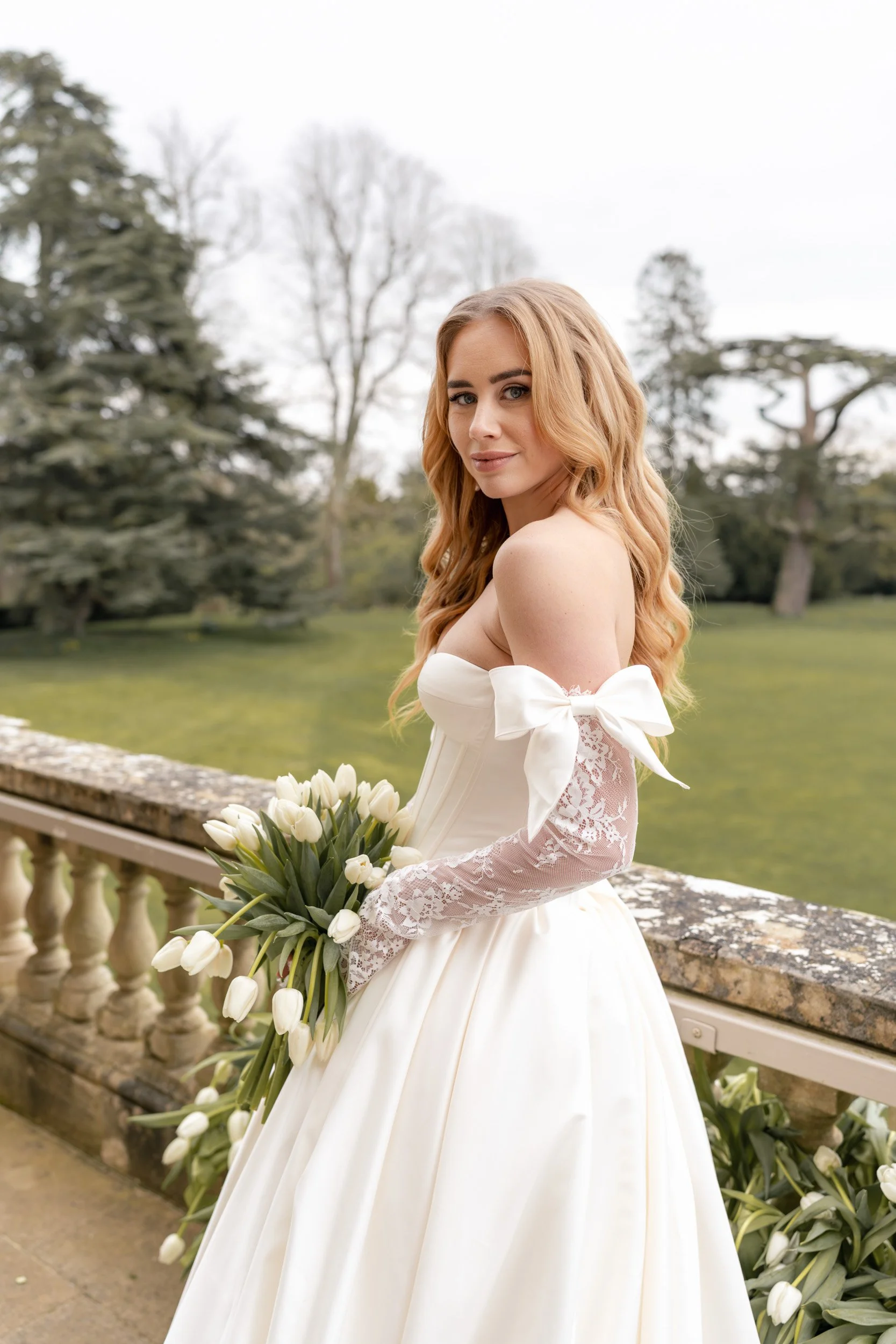 Portrait of a bride on floral balcony holding her bridal bouquet at her reception at Kirtlington Park in Oxfordshire