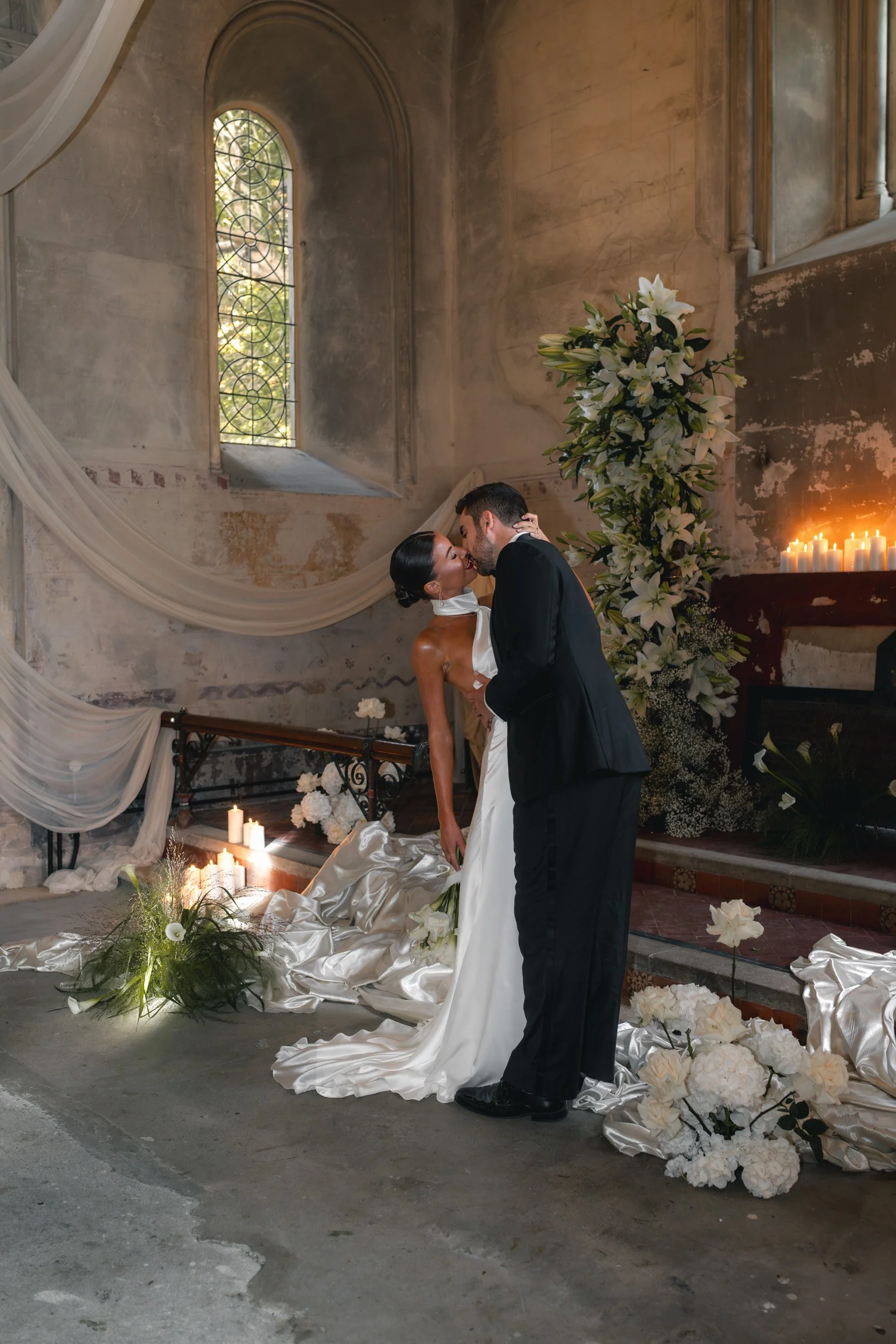 Bride and groom kissing in the window light in a candlelit wedding reception inside  The Bell Tower at The Elvetham Hotel in Hampshire