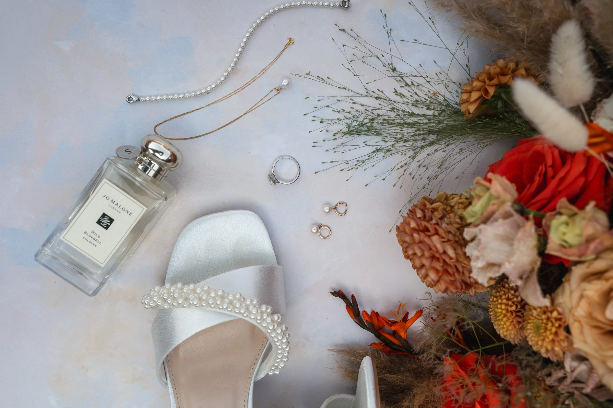 Wedding details including shoes, rings necklace, perfume and the brides bouquet taken at Rivervale Barn in Hampshire