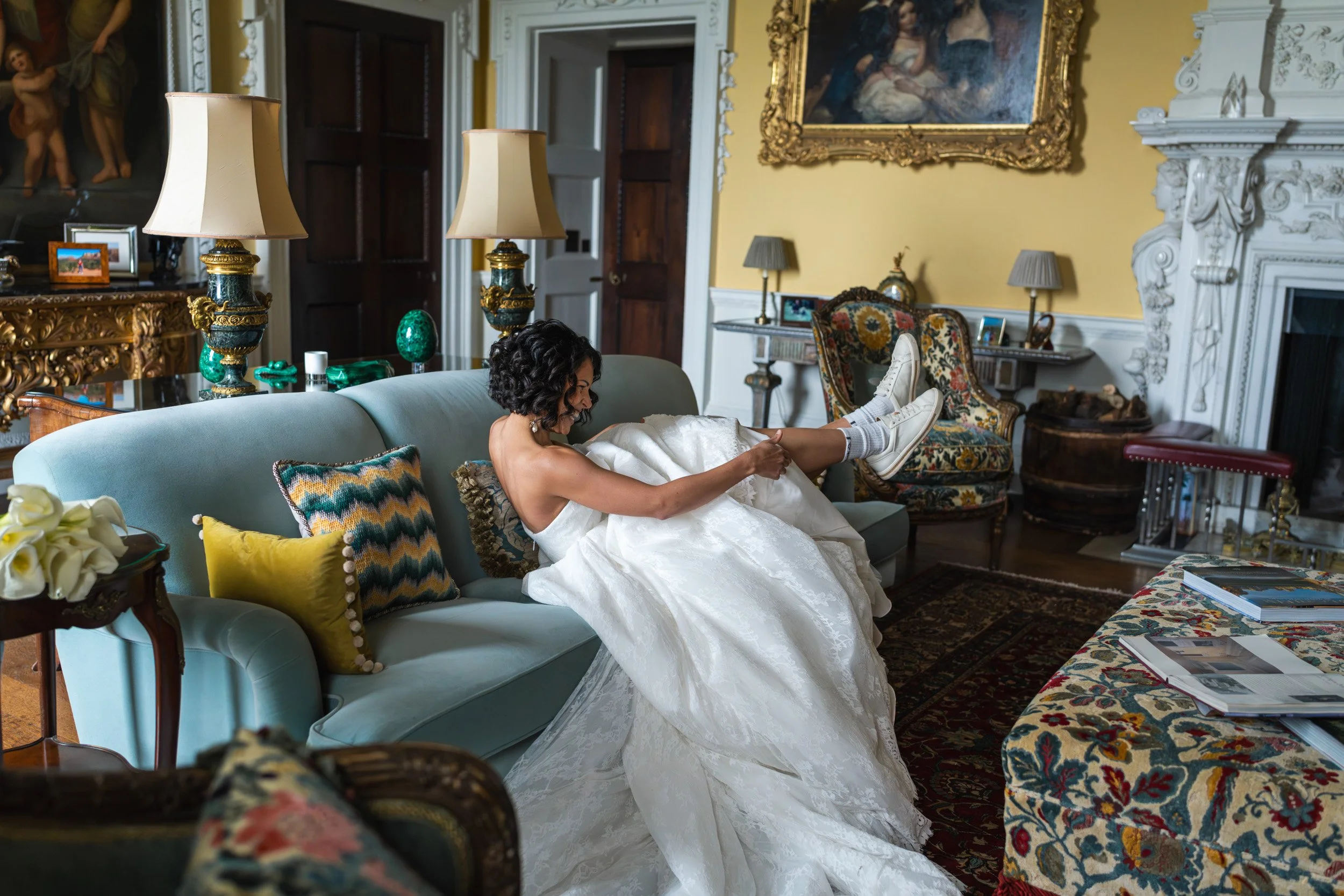 Bride laughing and revealing her trainers under her wedding dress at Kirtlington Park in Oxfordshire