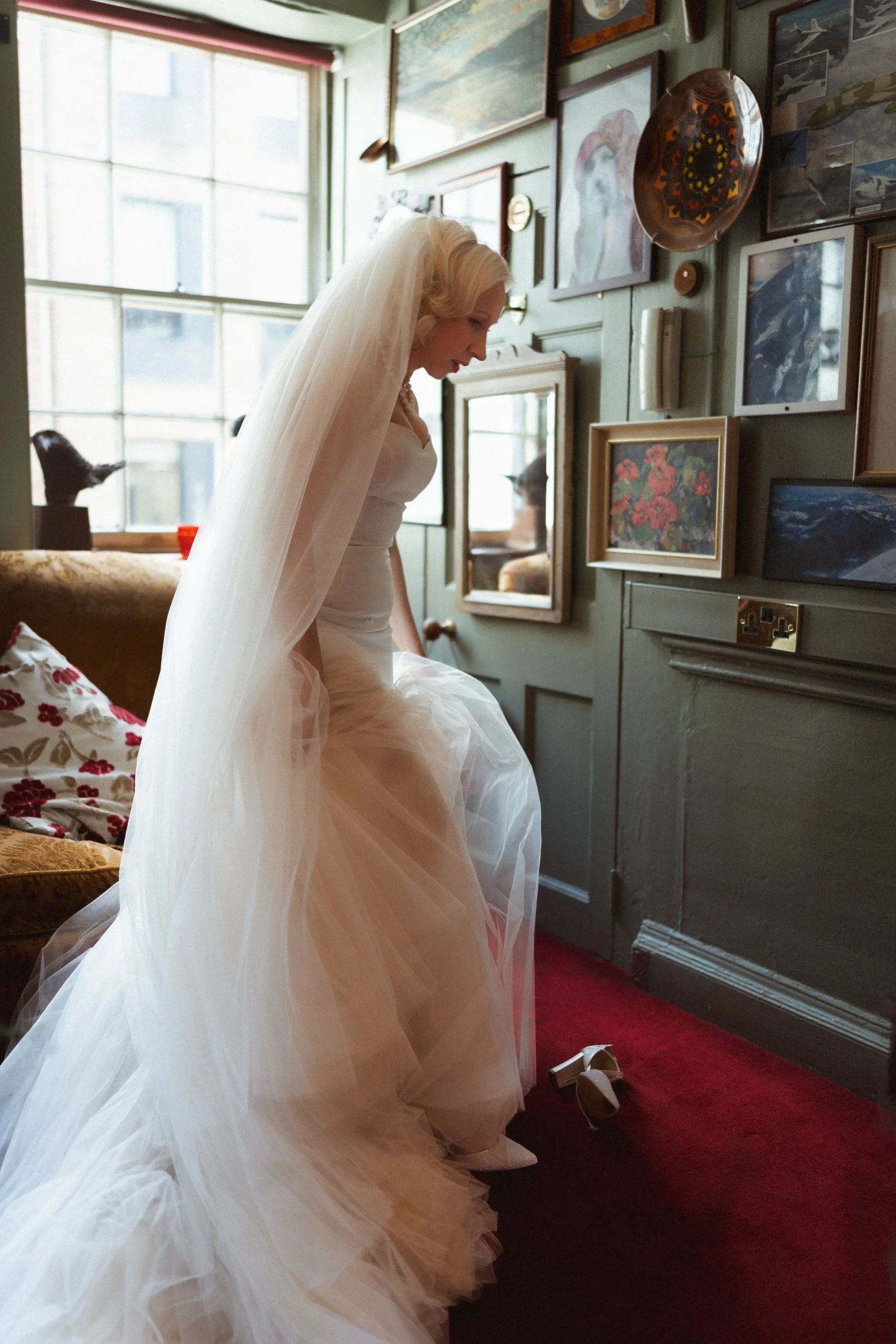 Bride putting her shoes on atThe Union Club in Soho London getting ready  to for her wedding ceremony at Fitzrovia Chapel 