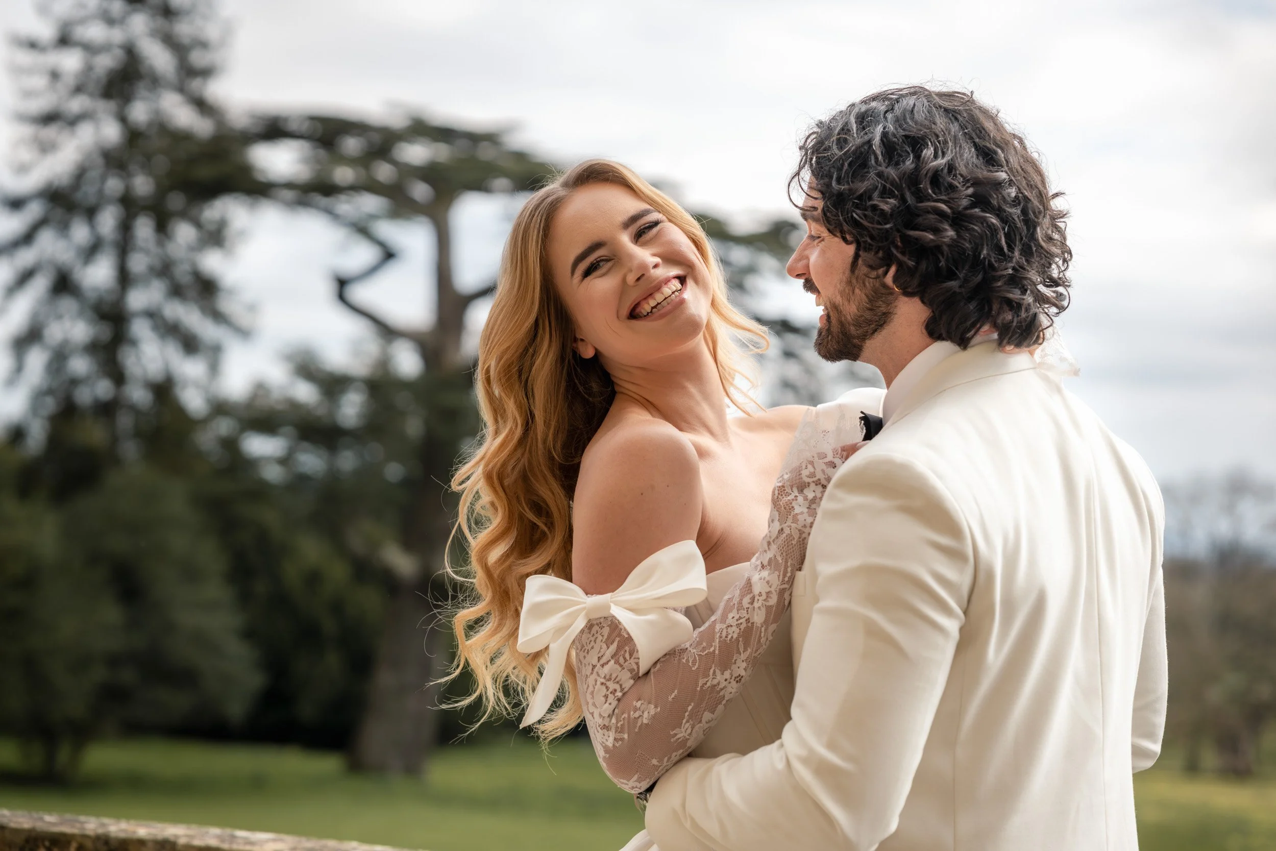 Bride smiling and laughing in the grooms arms on the balcony at Kirtlington Park in Oxfordshire