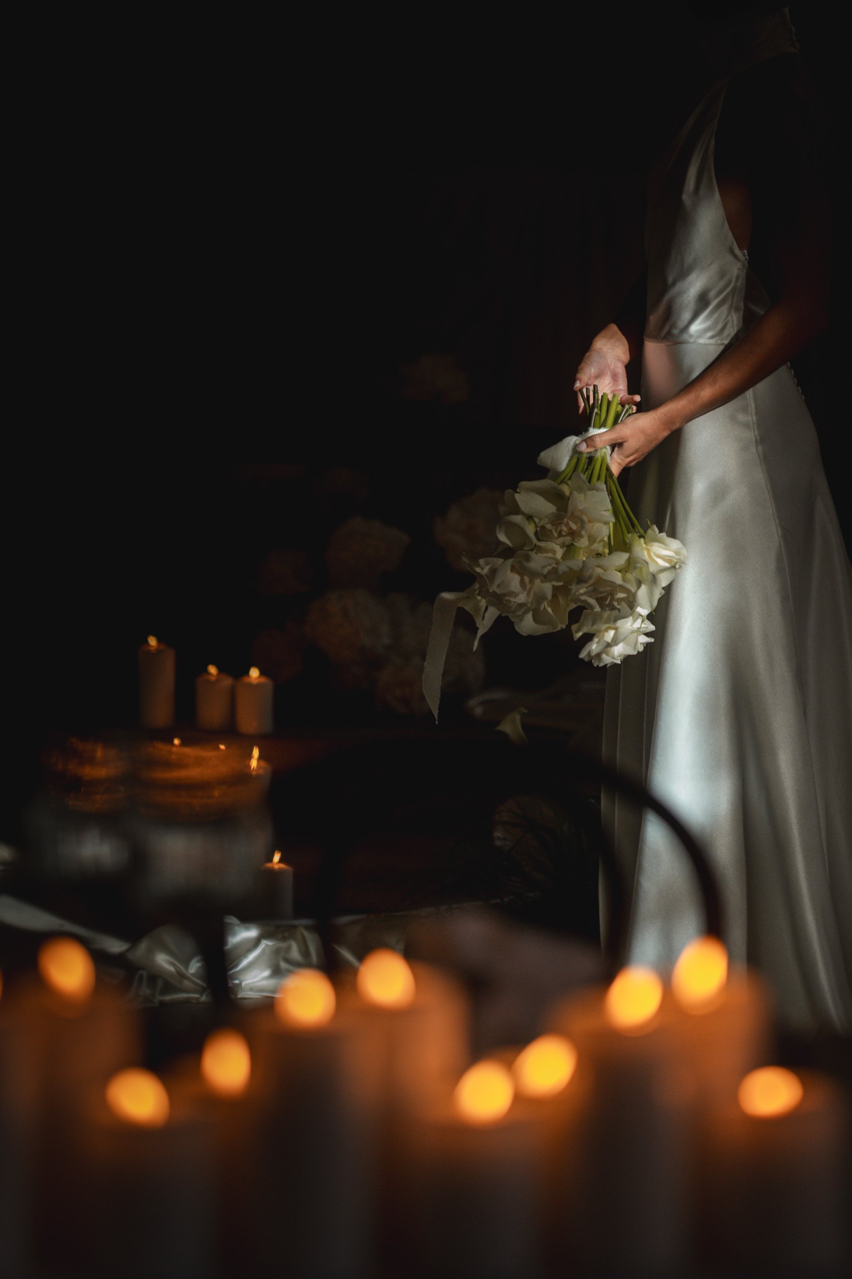 Bride holding her bouquet beside glowing candles inside The Bell Tower at The Elvetham Hotel in Hampshire
