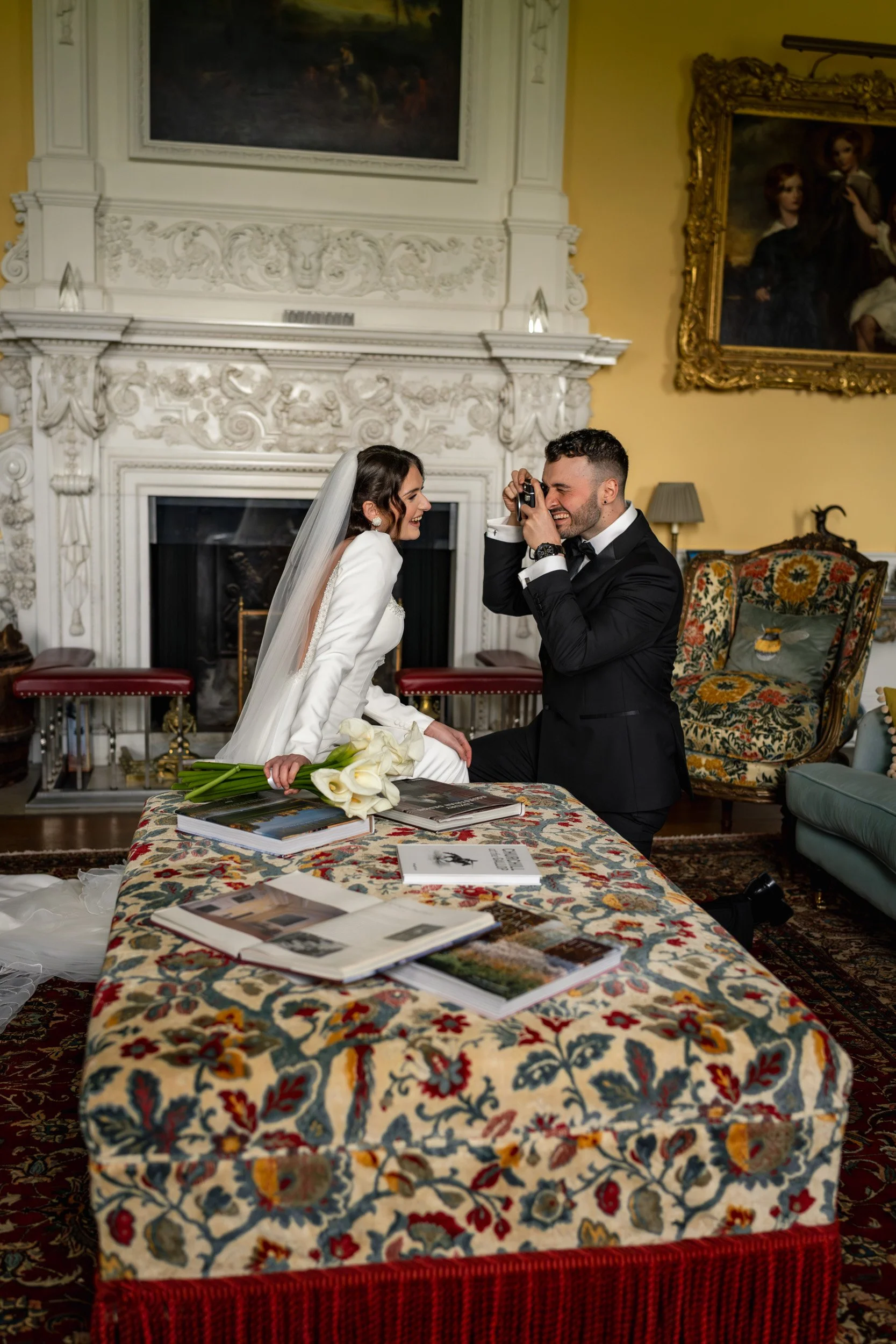 Groom taking a picture of his bride in an elegant room at Kirtlington Park in Oxfordshire