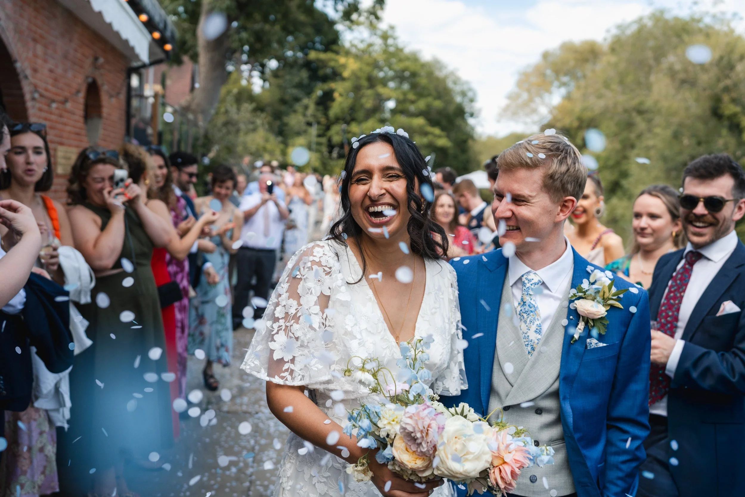 A close up of a bride and groom laughing through a joyful confetti throw outside Cherwell Boathouse in Oxford