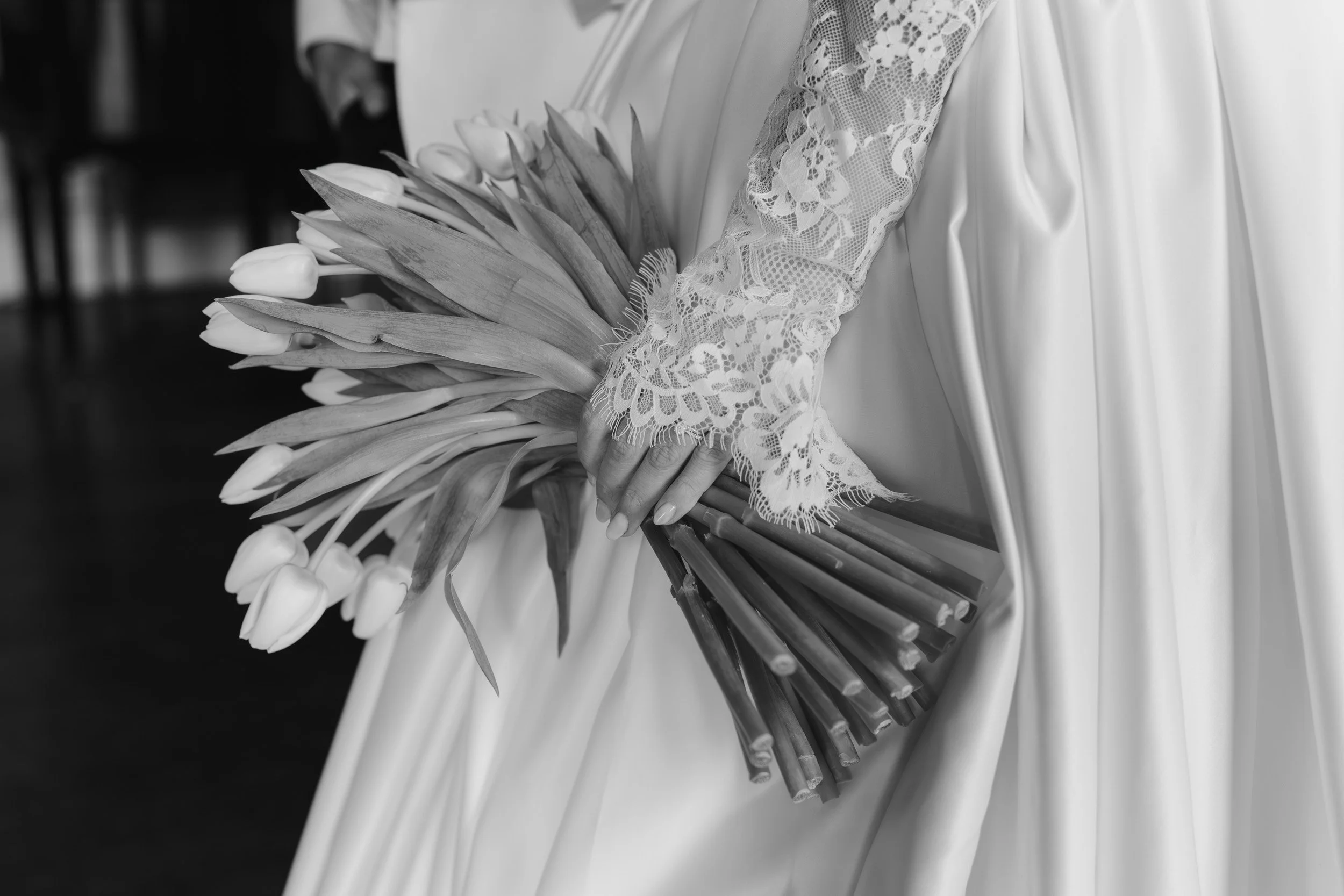 Close up of a Bride holding her wedding flowers with lace sleeves at Kirtlington Park in Oxfordshire