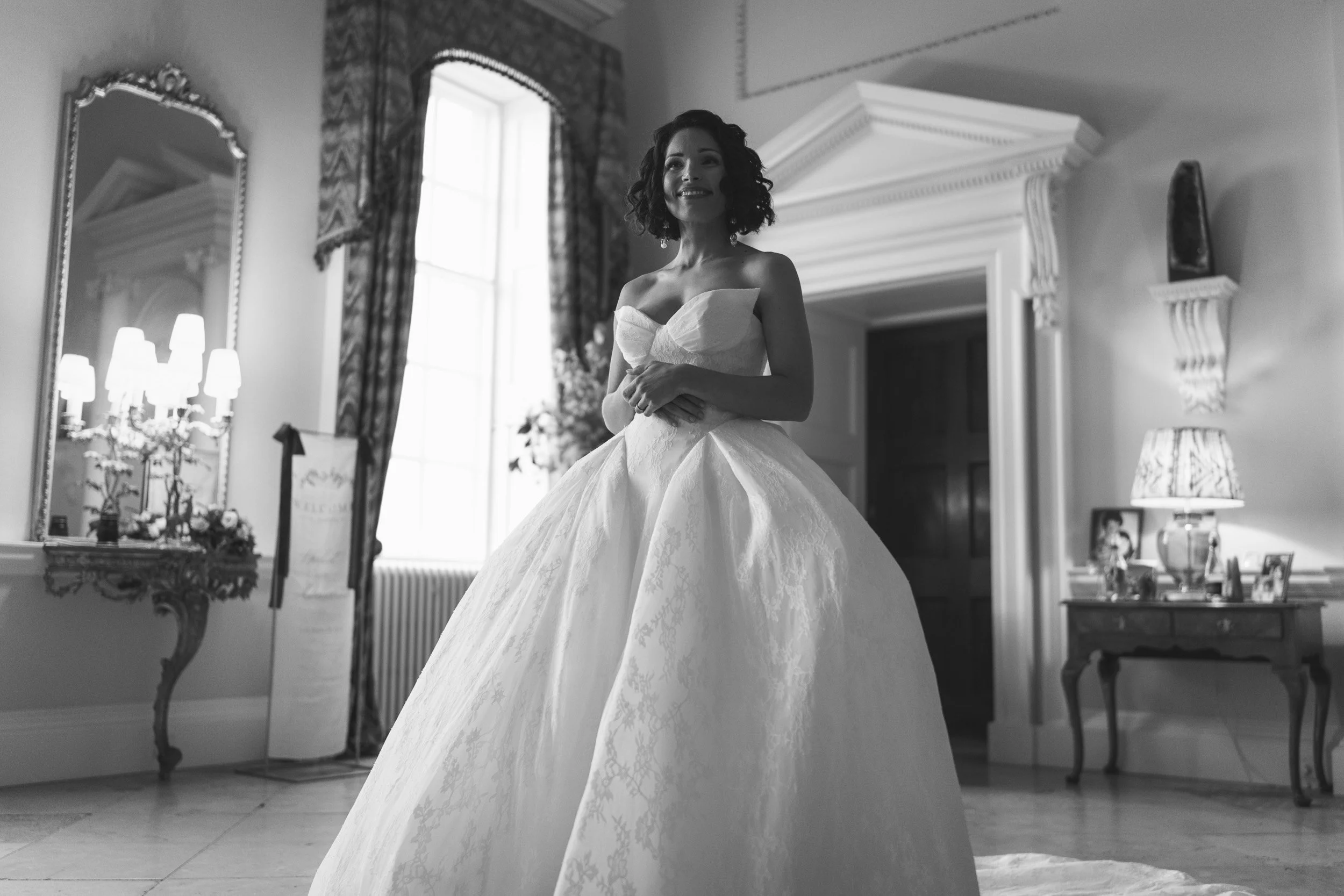 Bride smiling on at her wedding guests at the wedding reception at Kirtlington Park in Oxfordshire
