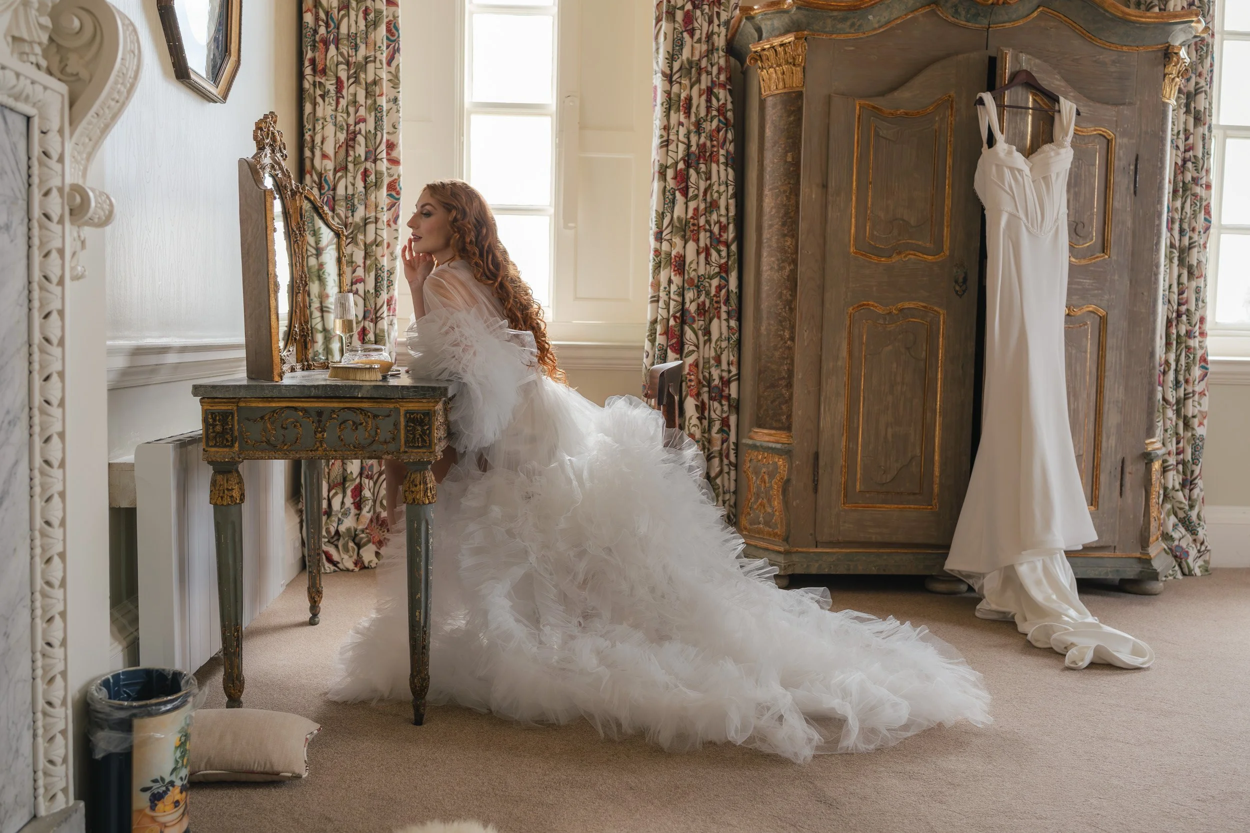 Bride getting ready and looking in the mirror at Kirtlington Park in Oxfordshire