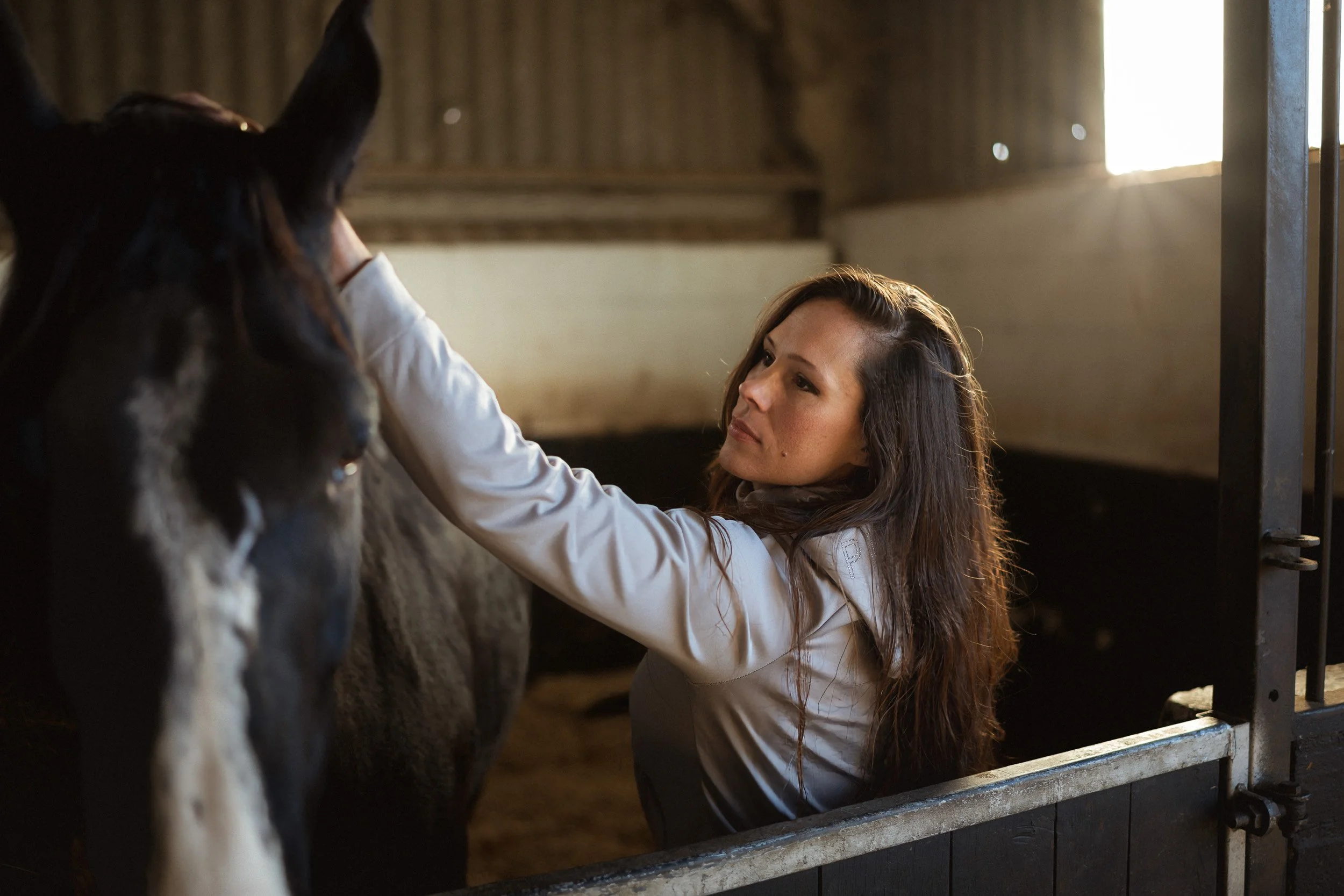 Equestrian fitness coach tacking up her  horse in the stables at Sean Hardy Horse Training in Great Missenden Buckinghamshire for a brand photoshoot