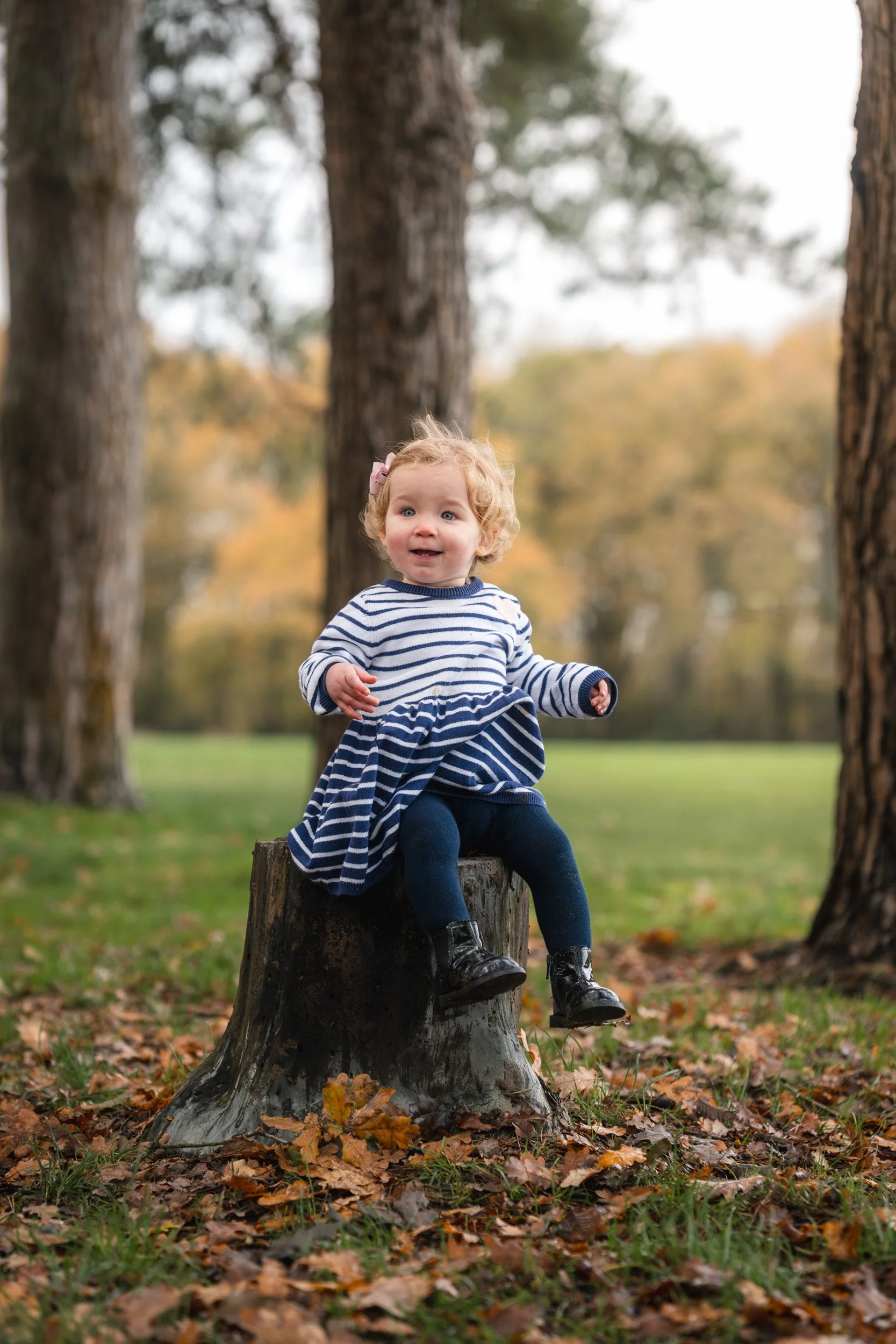 Little girl sat amongst the  autumn leaves during a natural outdoor family photoshoot in Amersham, Buckinghamshire