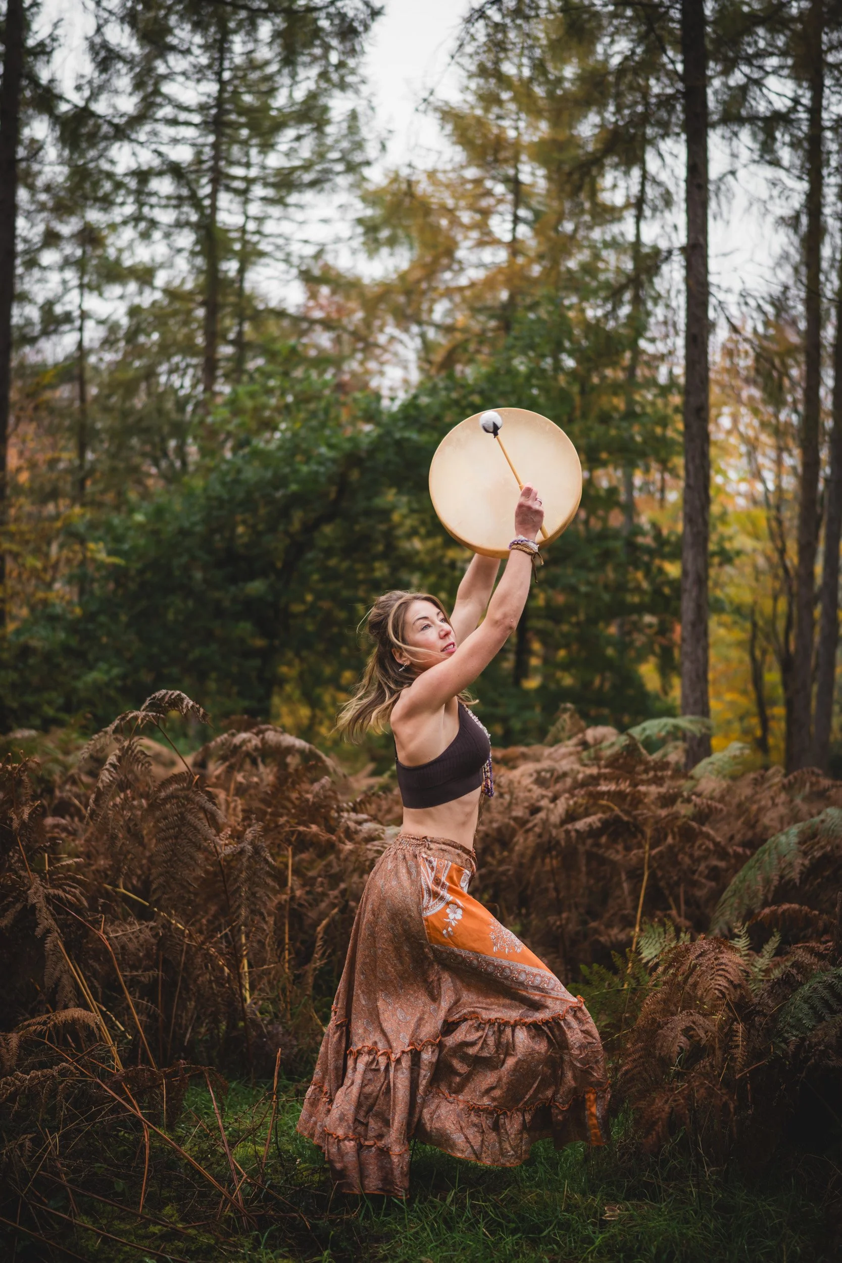 Sound healer playing a drum in the woodlands during a  personal branding shoot in Amersham Buckinghamshire