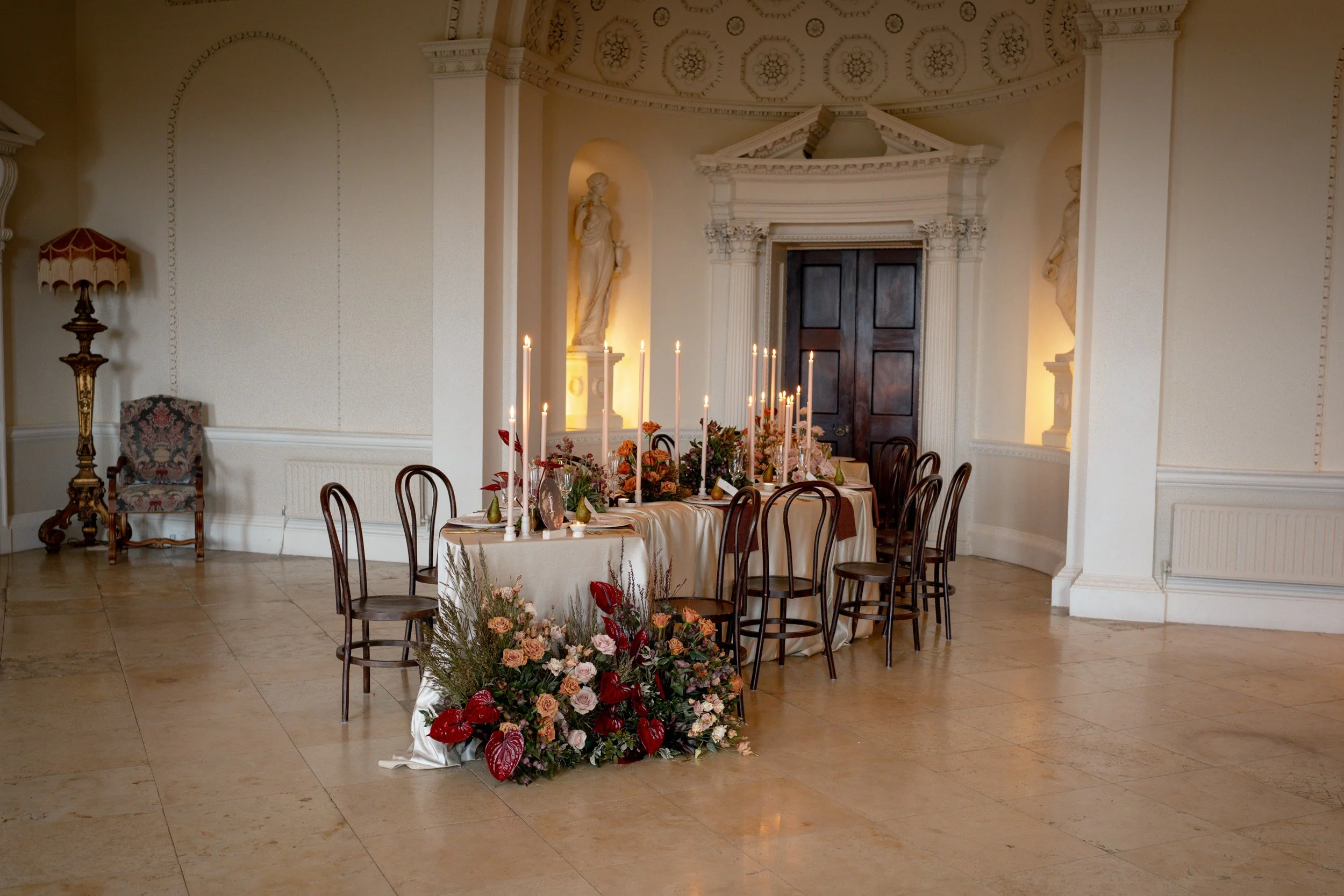 Wedding breakfast room at Kirtlington Park in Oxfordshire, styled with long curved silk draped tables, flowers and candle light beneath the domed ceiling