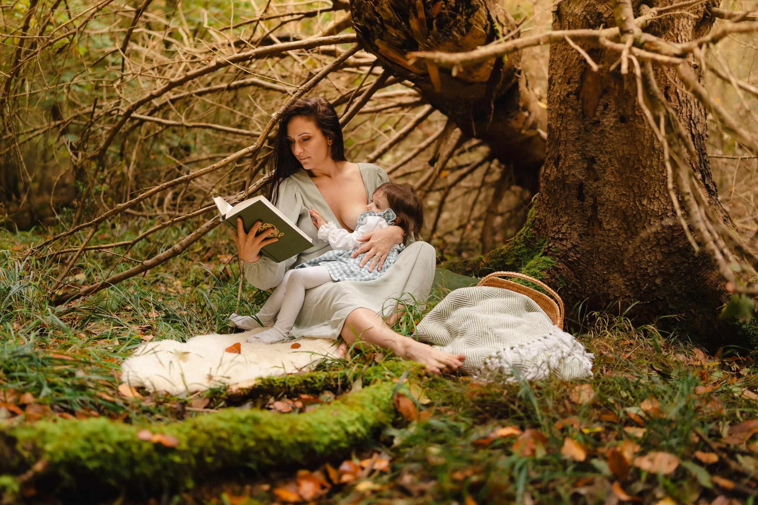 Mother reading to her baby during a peaceful woodland motherhood photography session in woods in Amersham, Buckinghamshire 