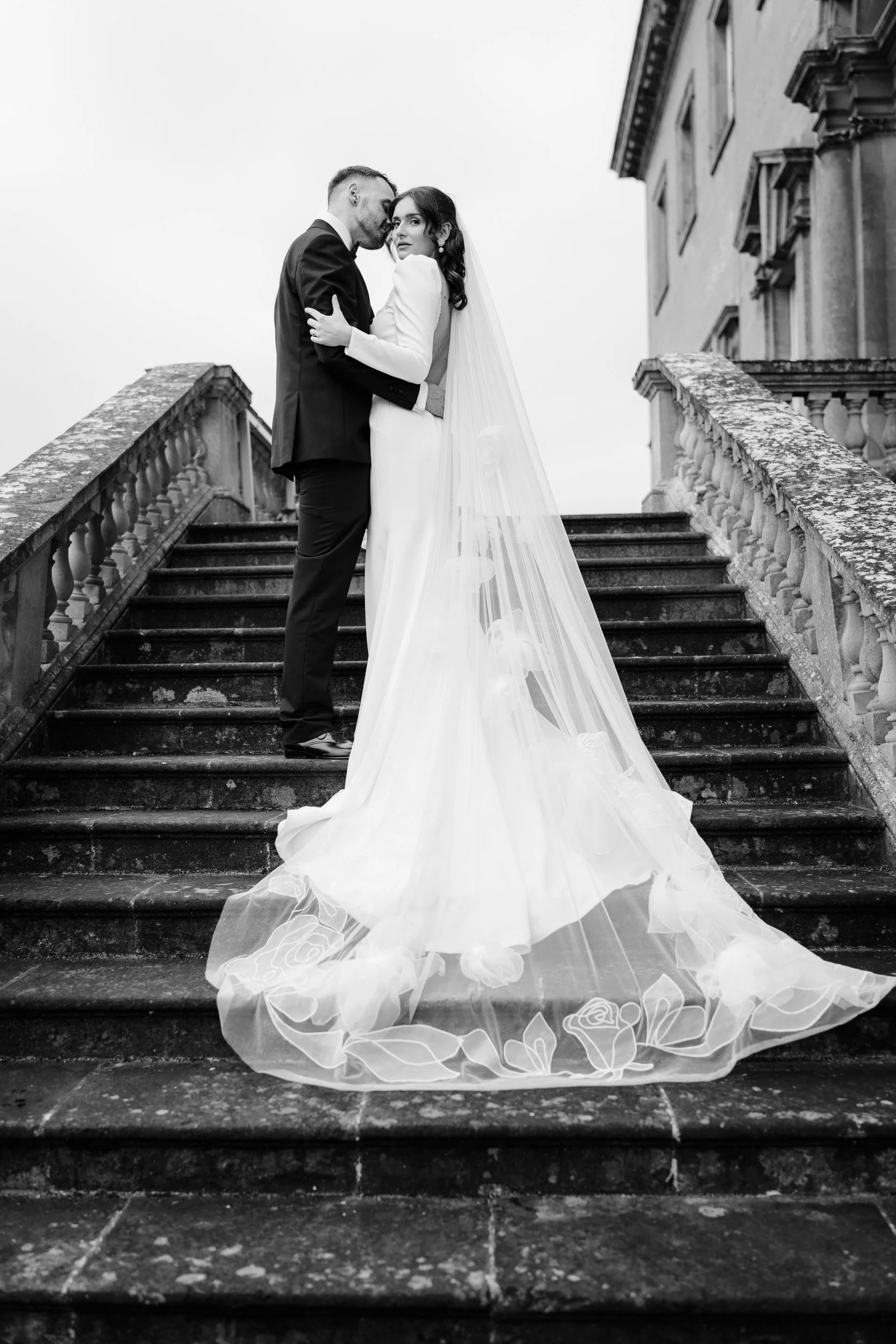 Bride and groom pausing for a kiss on stairs in the gardens at Kirtlington Park in Oxfordshire