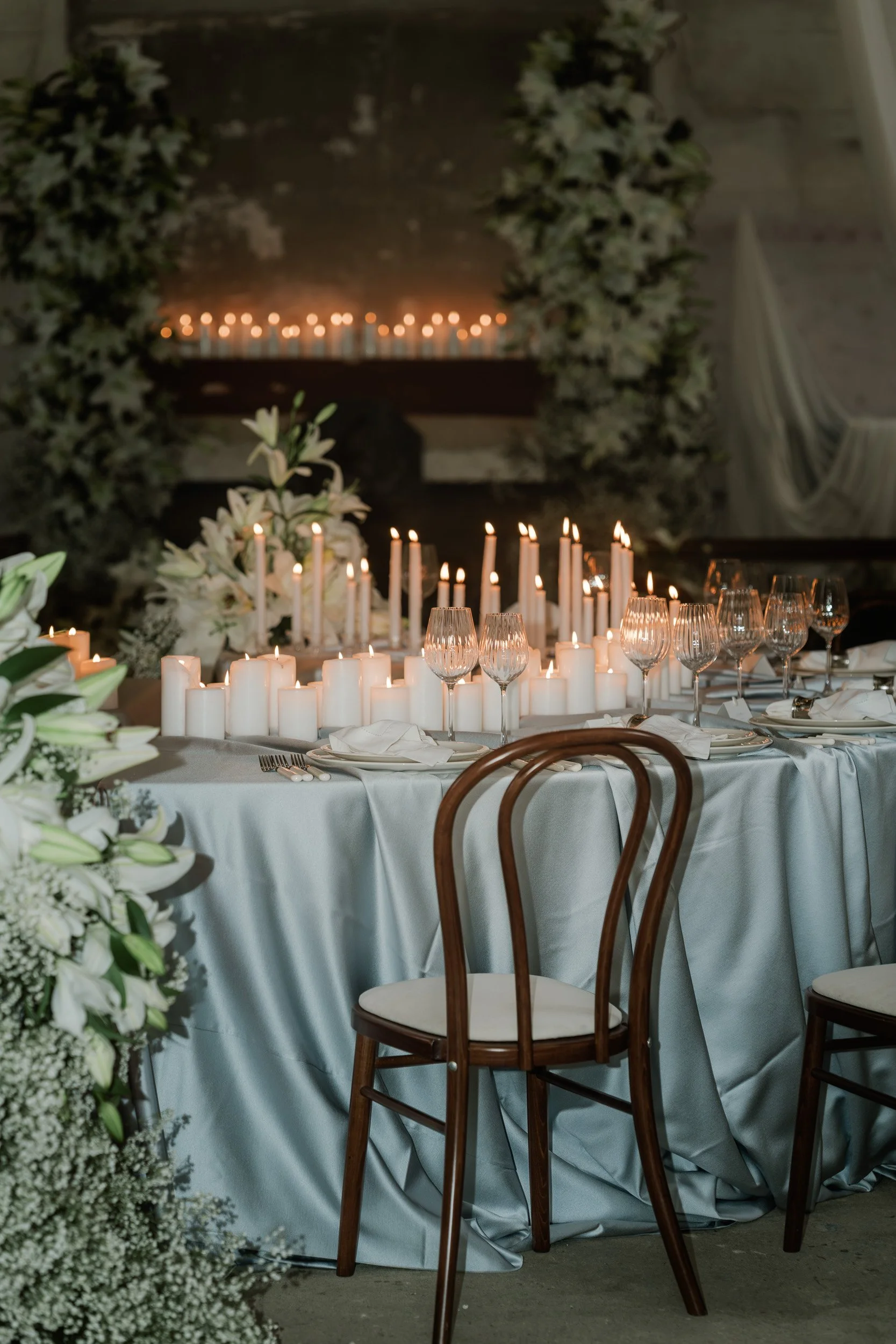 A close up of a  candlelit reception room with flowing drapery and long banquet tables inside The Bell Tower at The Elvetham Hotel in Hampshire