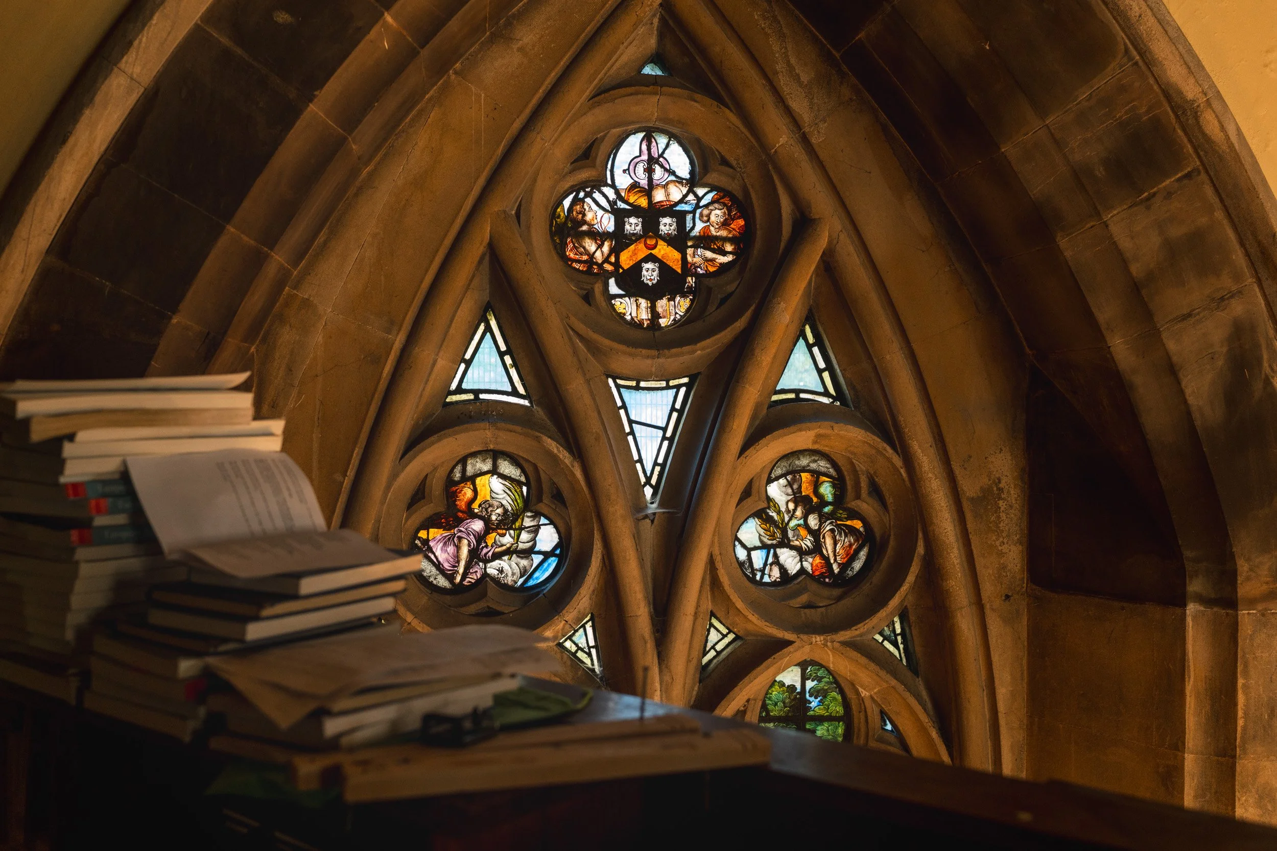 Stained glass window and gothic architecture inside an Oxford University college chapel during a wedding ceremony in Oxford, Engand