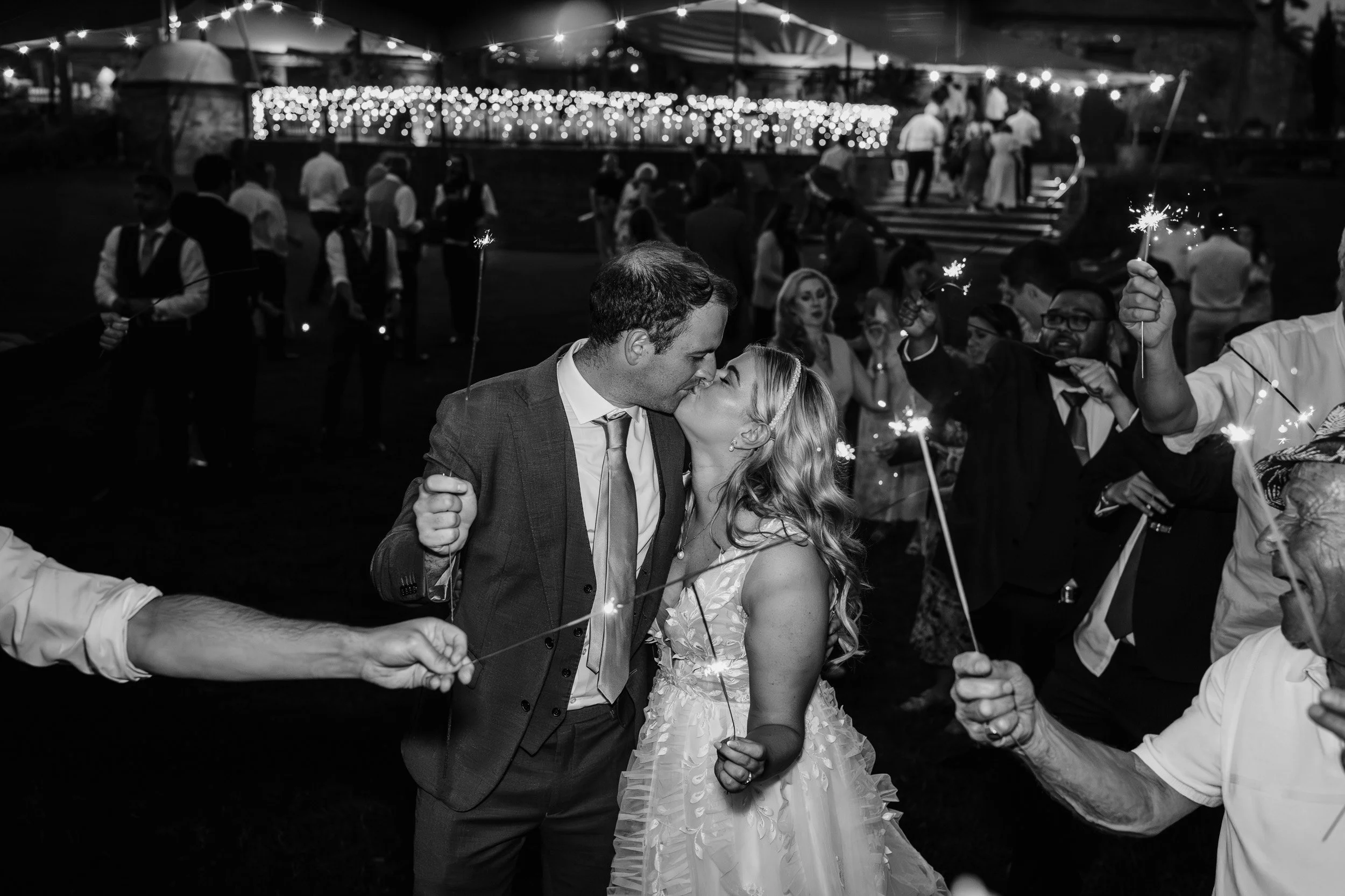 Bride and groom kiss at the end of a sparkler arch held by their wedding guests at the end of their wedding reception at Wasing Park in Berkshire