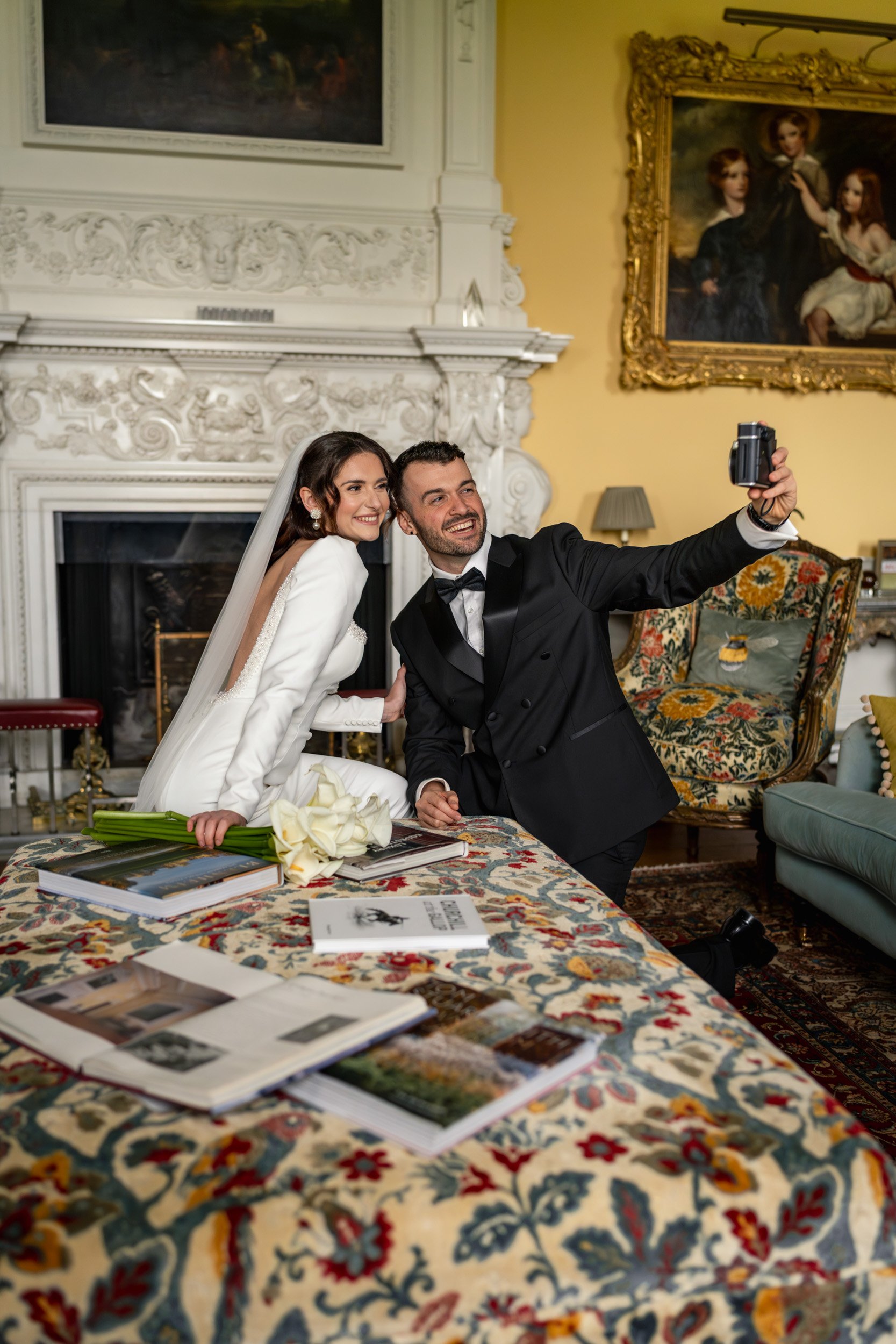 Bide and groom taking a selfie in an elegant room at Kirtlington Park in Oxfordshire