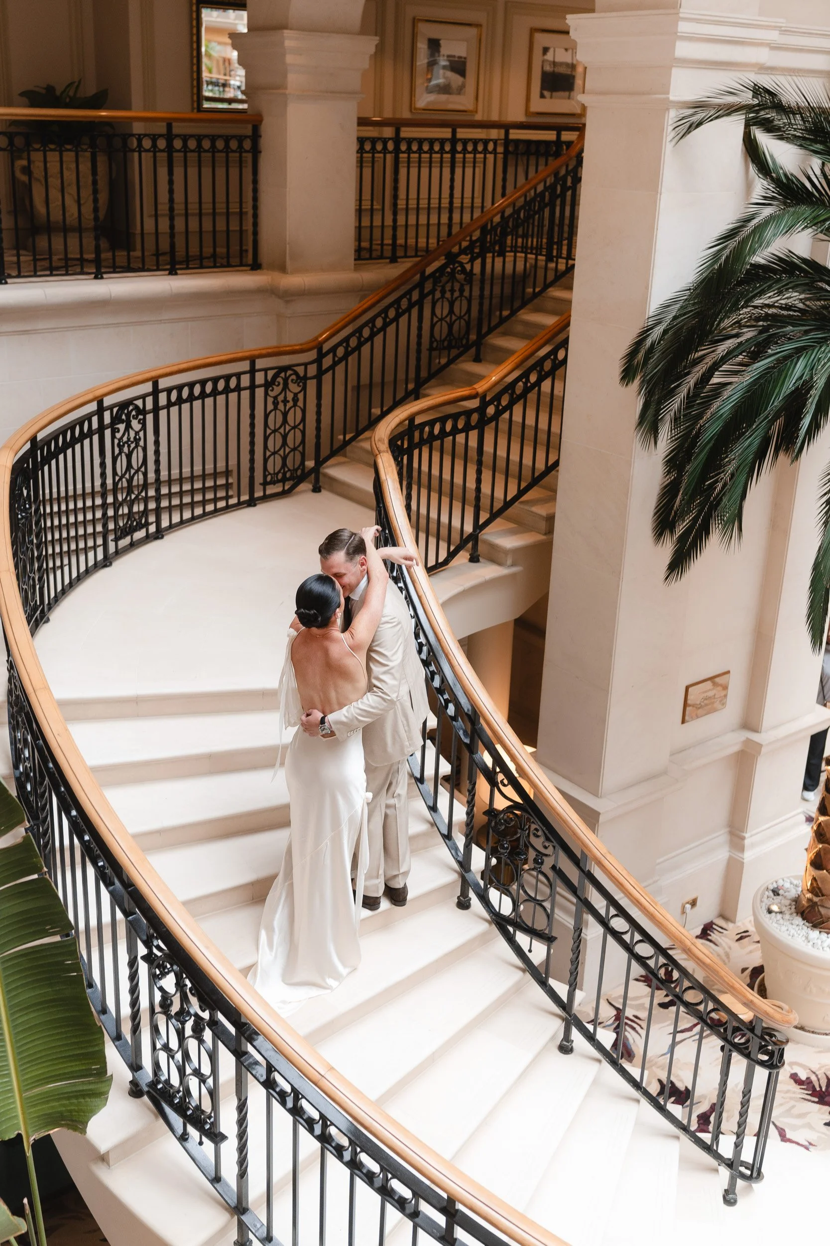 Bride and groom on the grand staircase  at The Landmark Hotel,  London in Marylebone kissing