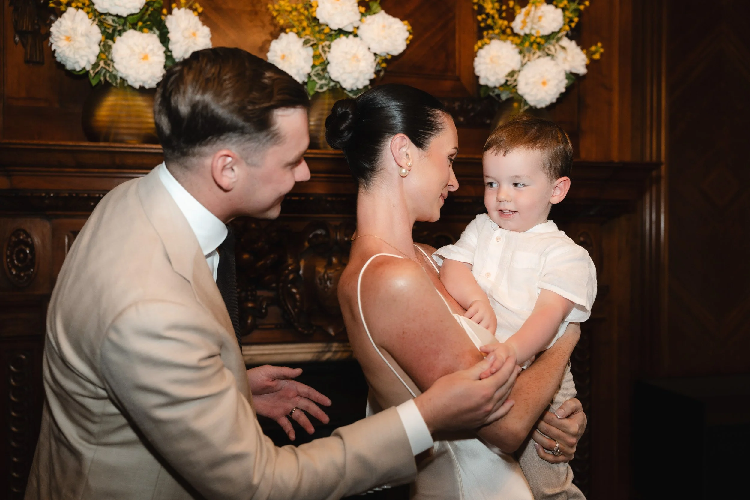 Newly married Bride and Groom cuddling their toddler after their wedding ceremony at Marylebone Town Hall Registry Office in London  
