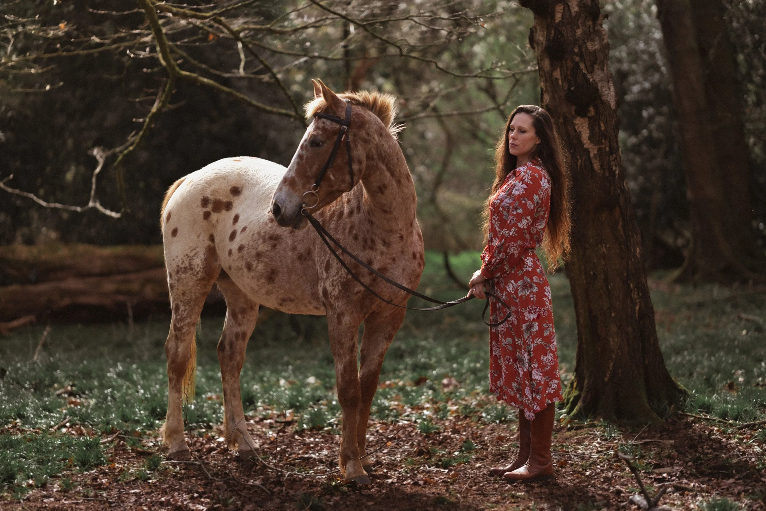 Equestrian fitness coach standing with Appaloosa polo pony in a woodland during a branding photoshoot in Penn Buckinghamshire