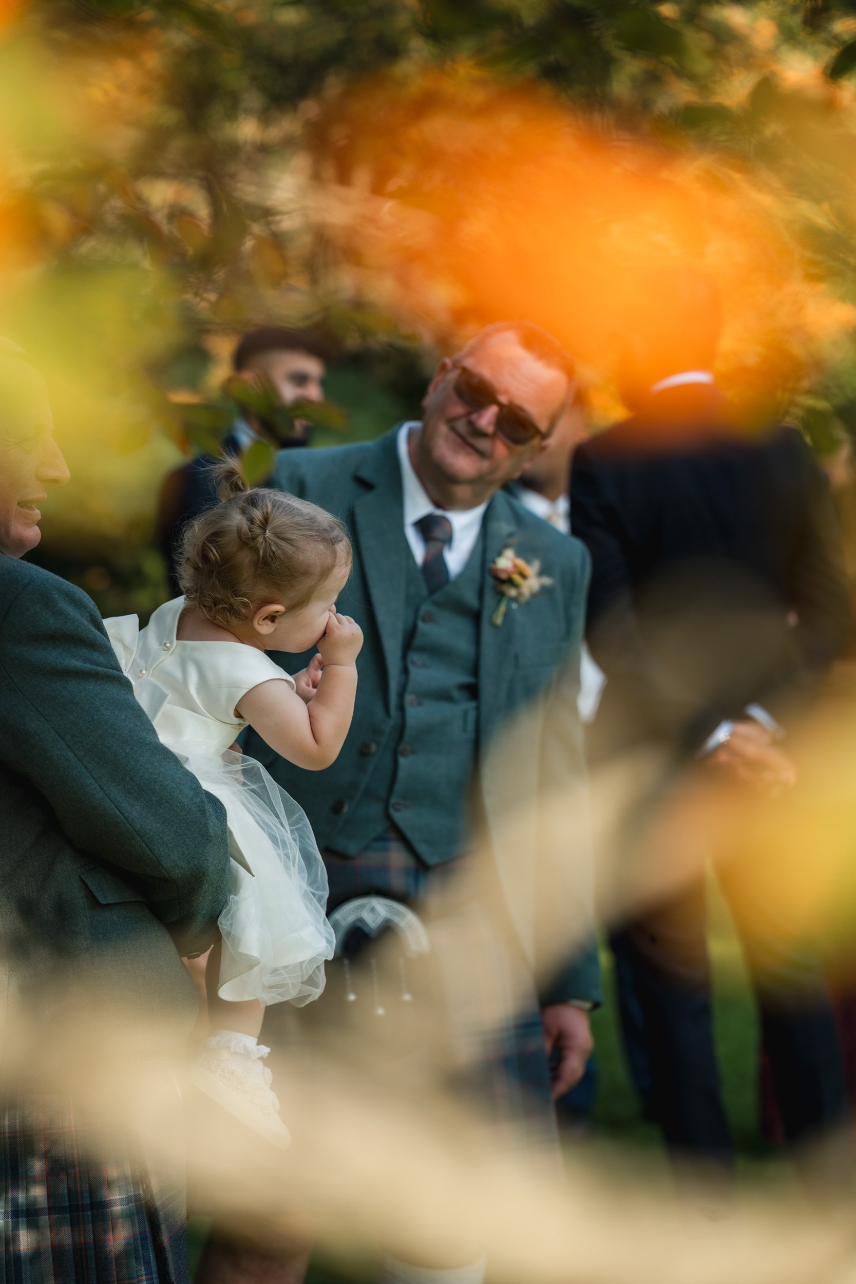 Brides father talking to their baby in the gardens Rivervale Barn in Hampshire during the family portrait session