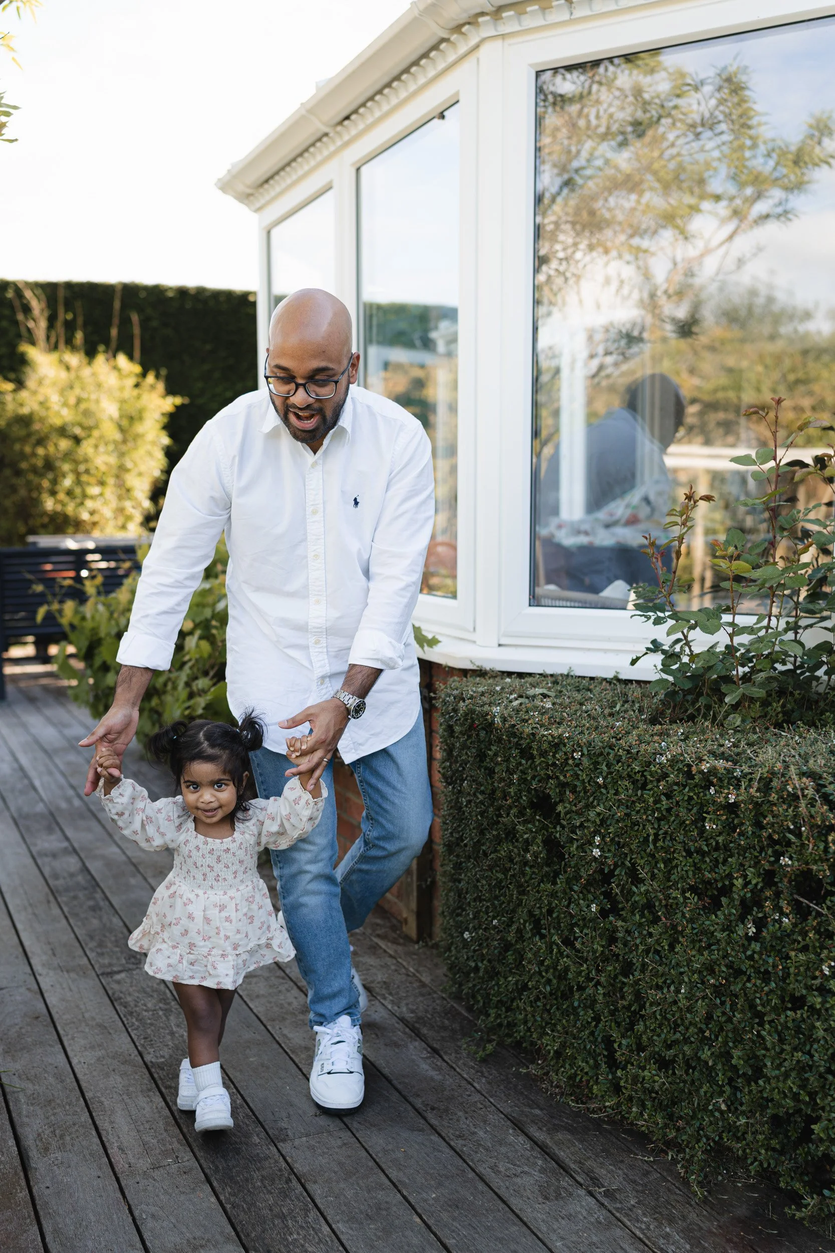 a little girl walking with the help of her dad at a relaxed at-home family photography session in Amersham, Buckinghamshire 