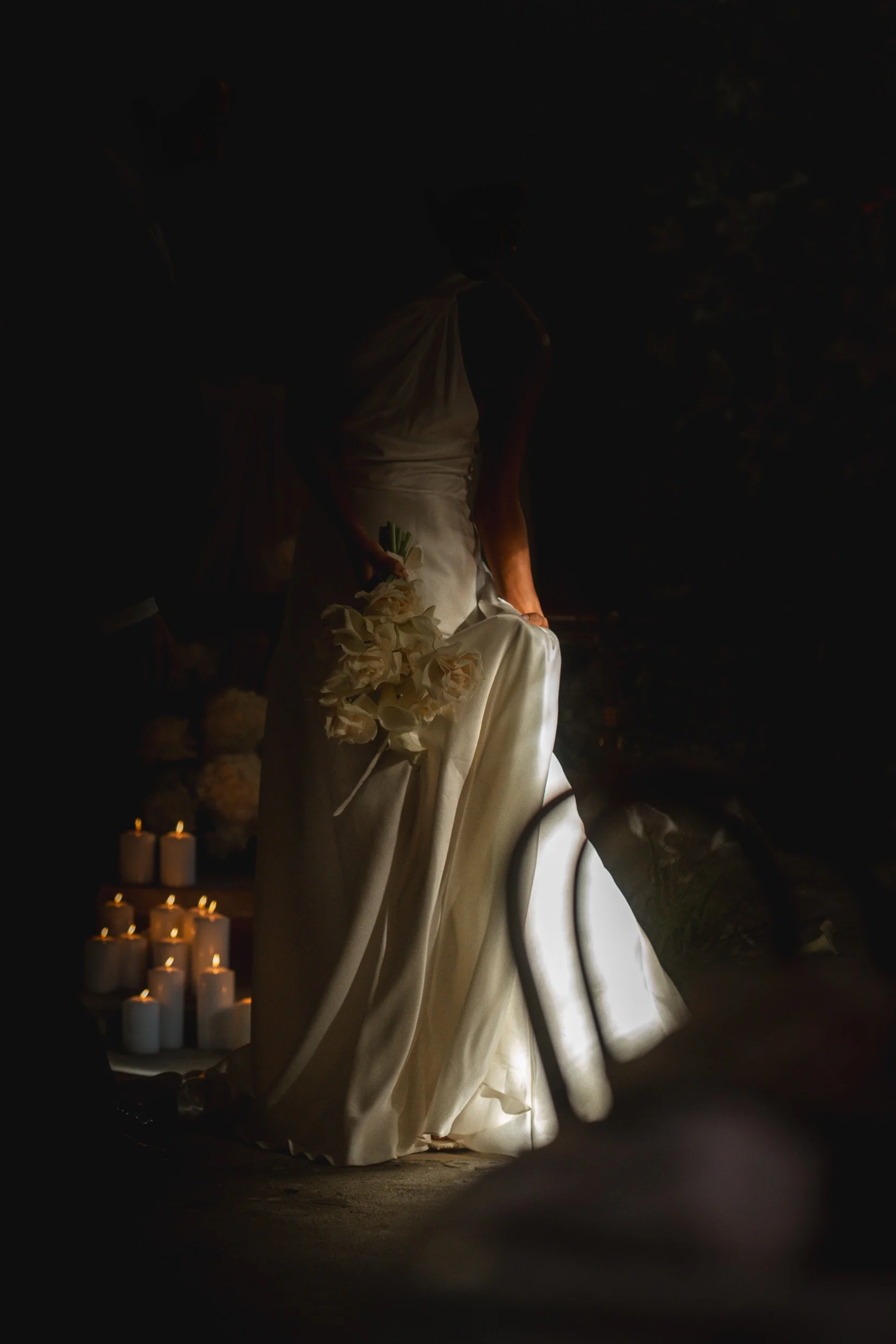 Bride holding her dress beside glowing candles inside The Bell Tower at The Elvetham Hotel in Hampshire
