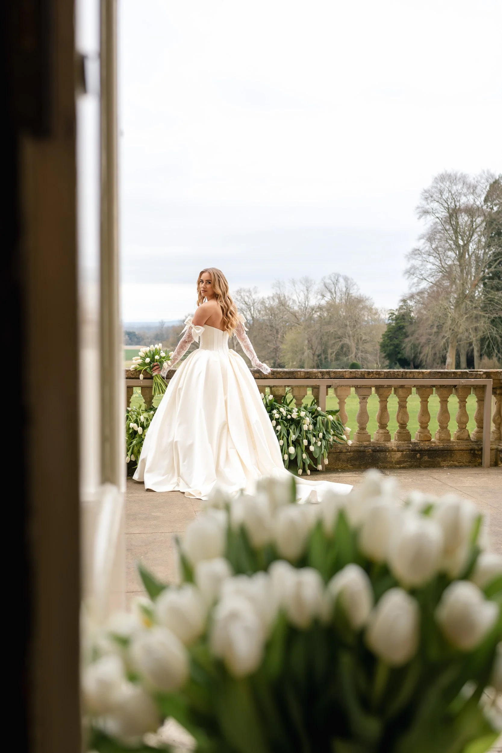 Bride looking back from the floral balcony to her reception at Kirtlington Park in Oxfordshire