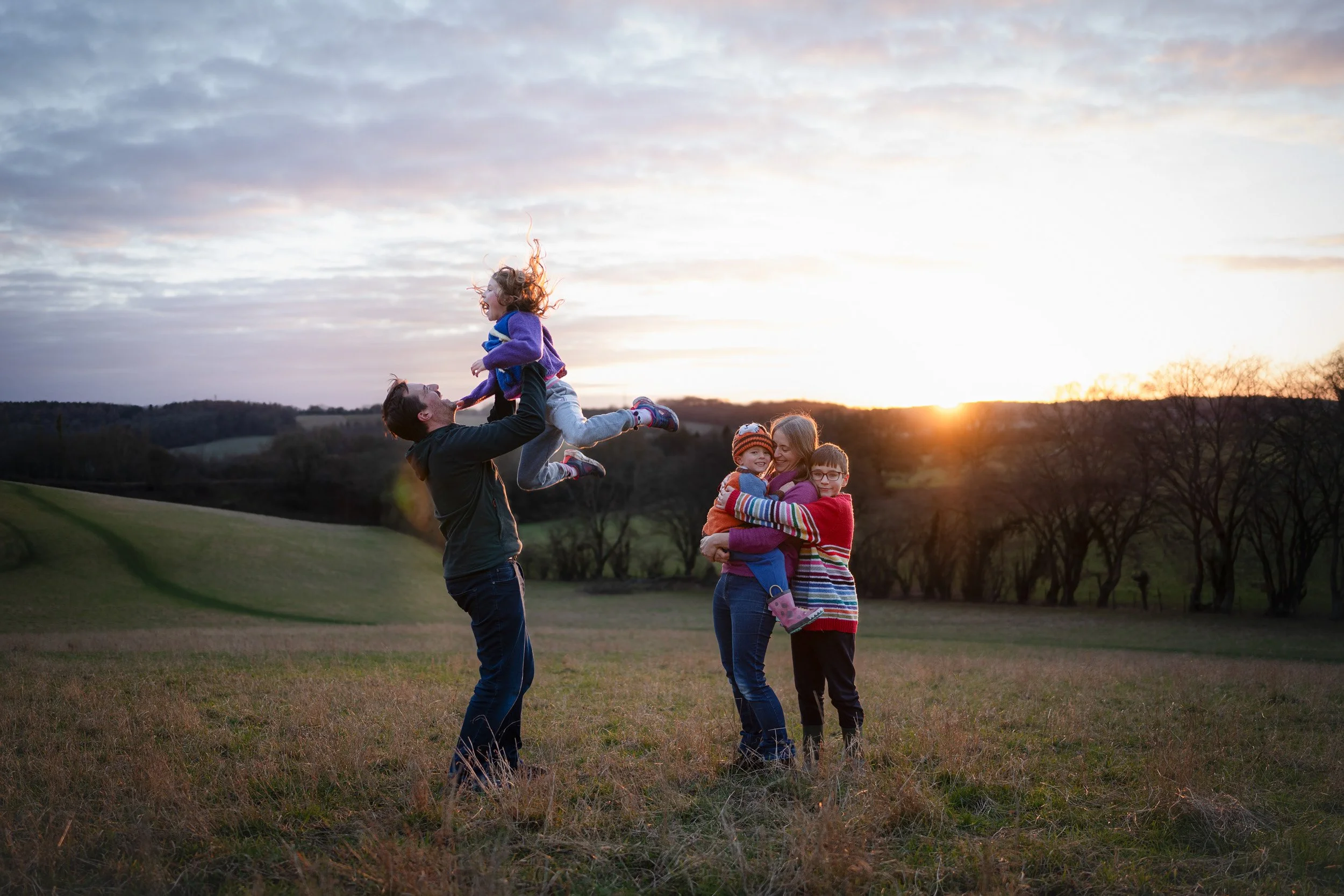  Family playing together in a  field at sunset during an outdoor family photography session in Amersham, Buckinghamshire