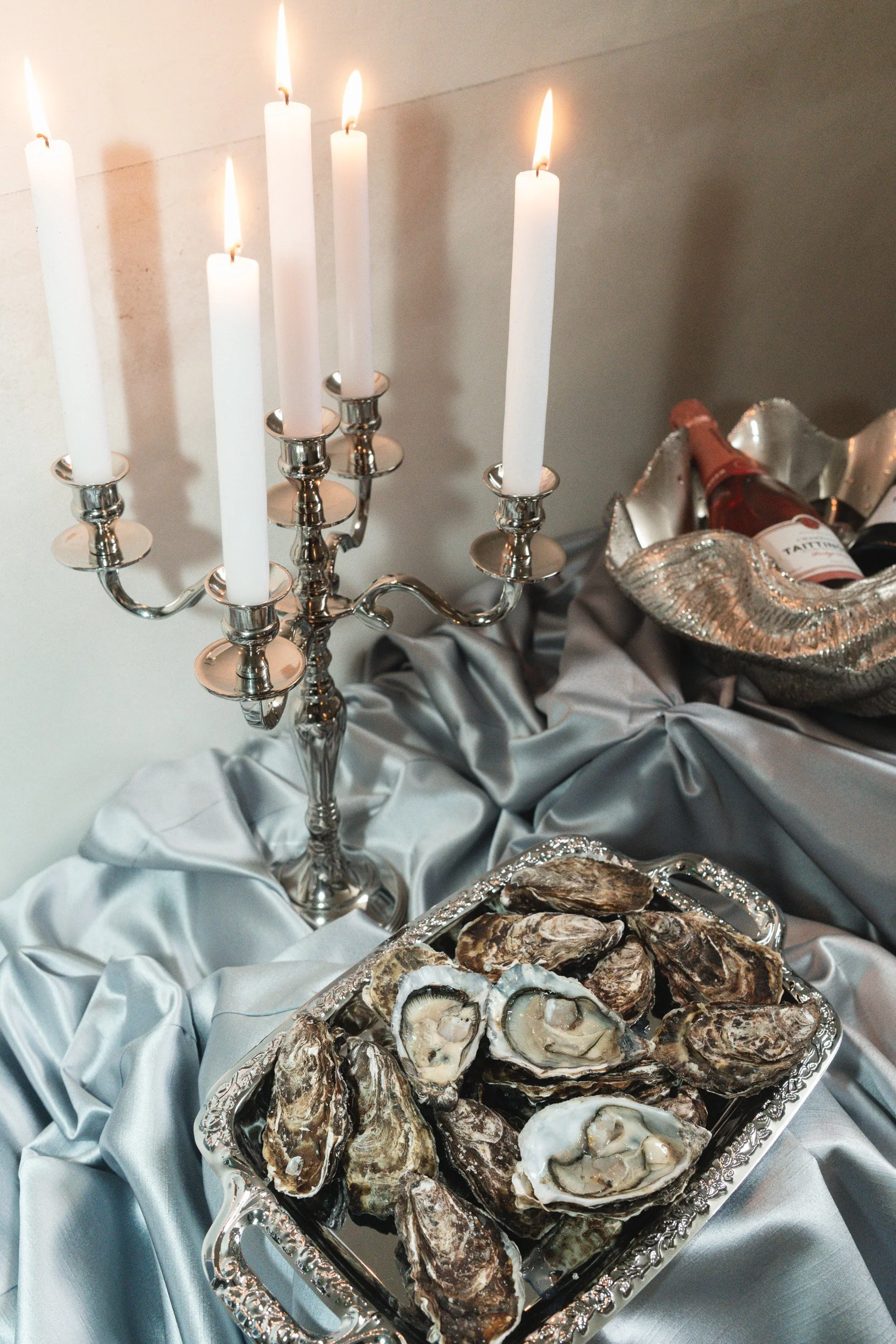 Wedding banquet table details with a lit candelabra and oysters on silk 