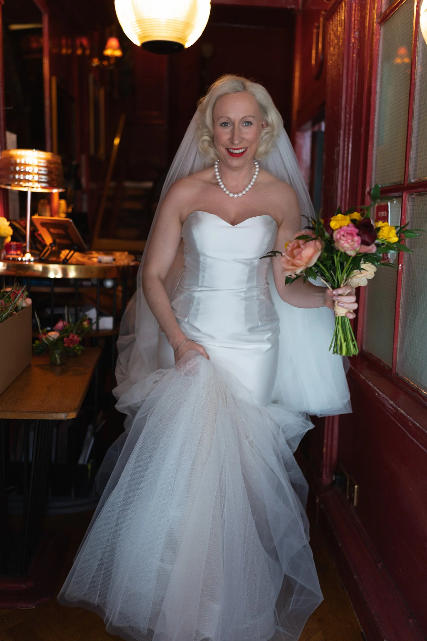 Excited bride and her bouquet leaving  The Union Club in Soho, London to go to  Fitzrovia Chapel 