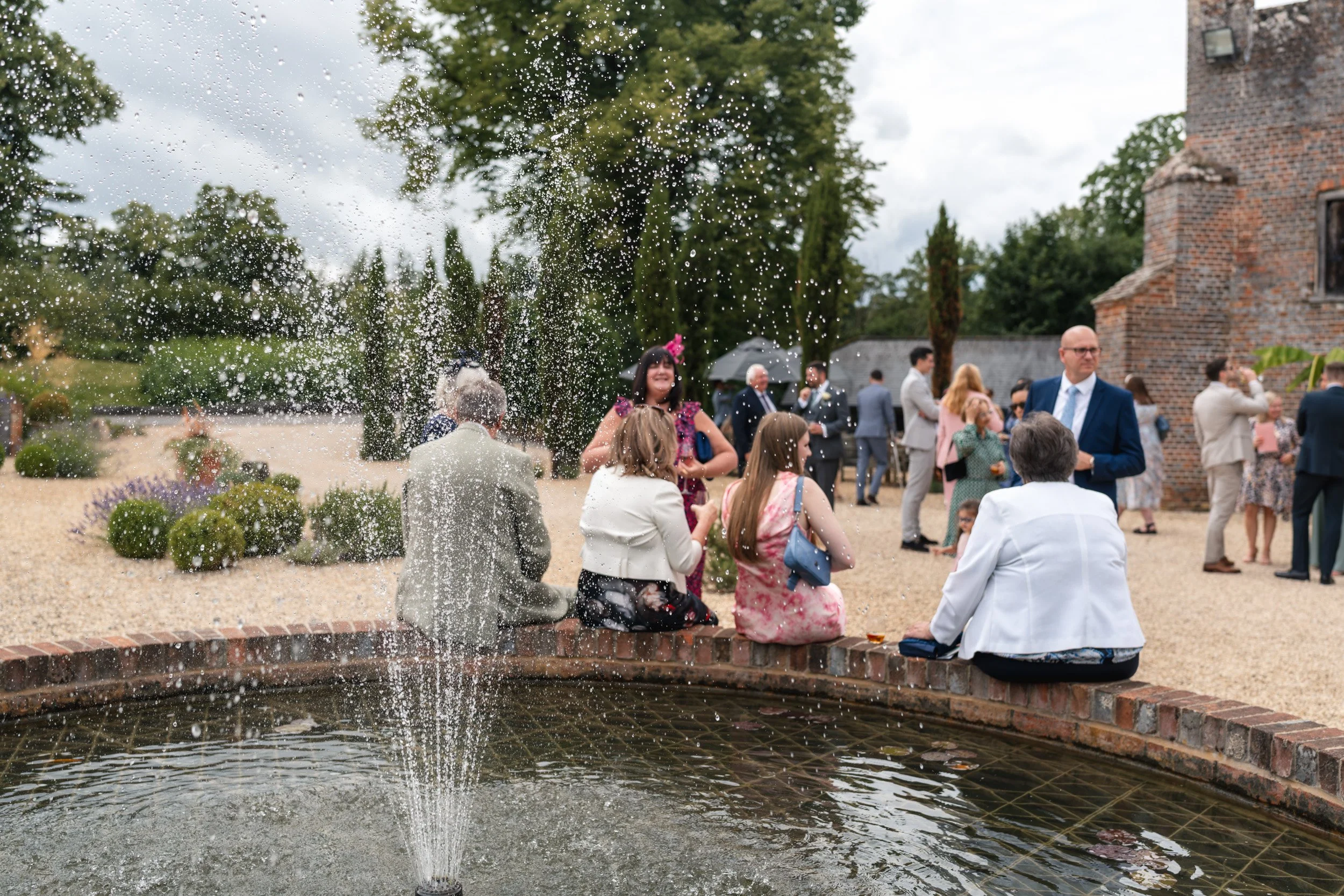 Wedding guests gathered around the fountain in the main courtyard during the drinks reception at Wasing Park in Berkshire