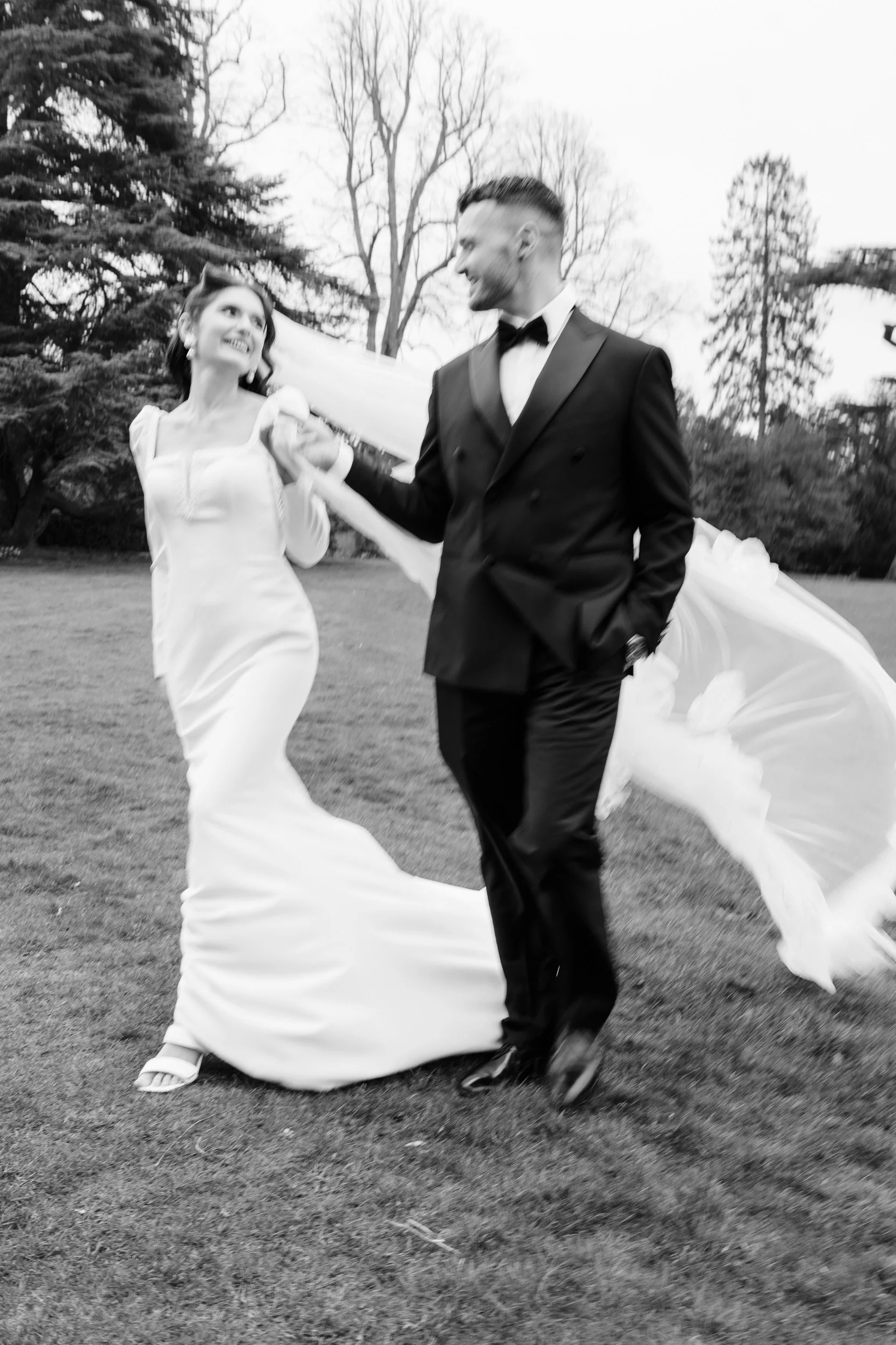 Bride and groom walking hand in hand gazing at each other with soft motion blur in the gardens of Kirtlington Park in Oxfordshire
