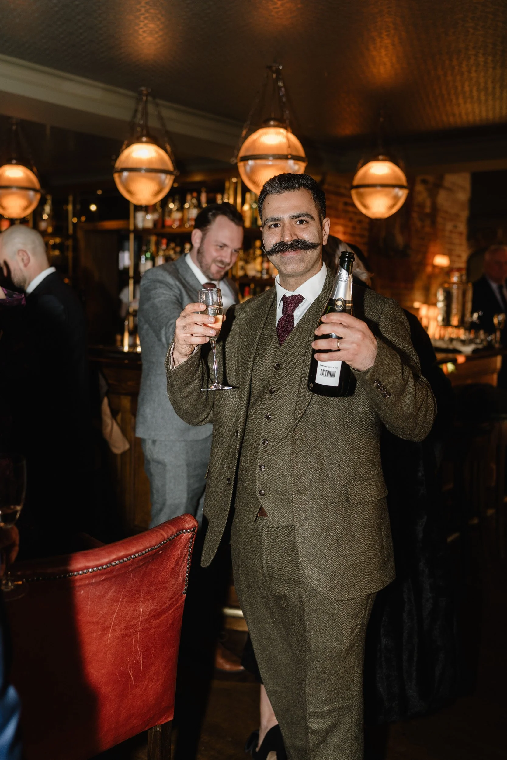 Best man with a bottle of champagne during the reception at The Bedford Arms in Chenies, Buckinghamshire