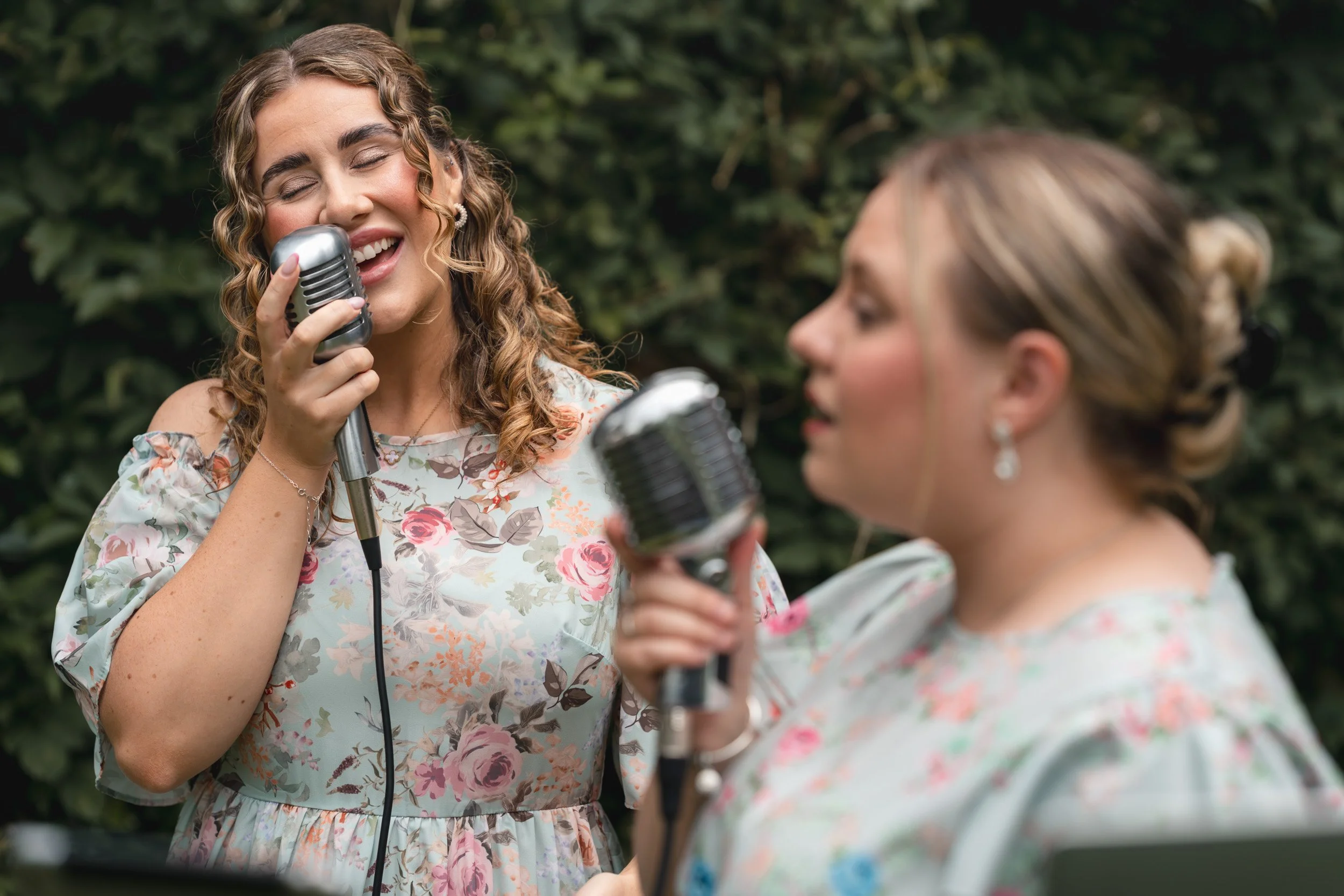 Harmony Wedding Duo singing with vintage microphones as the bride walks down the aisle at an out door wedding ceremony at Wasing Park in Berkshire