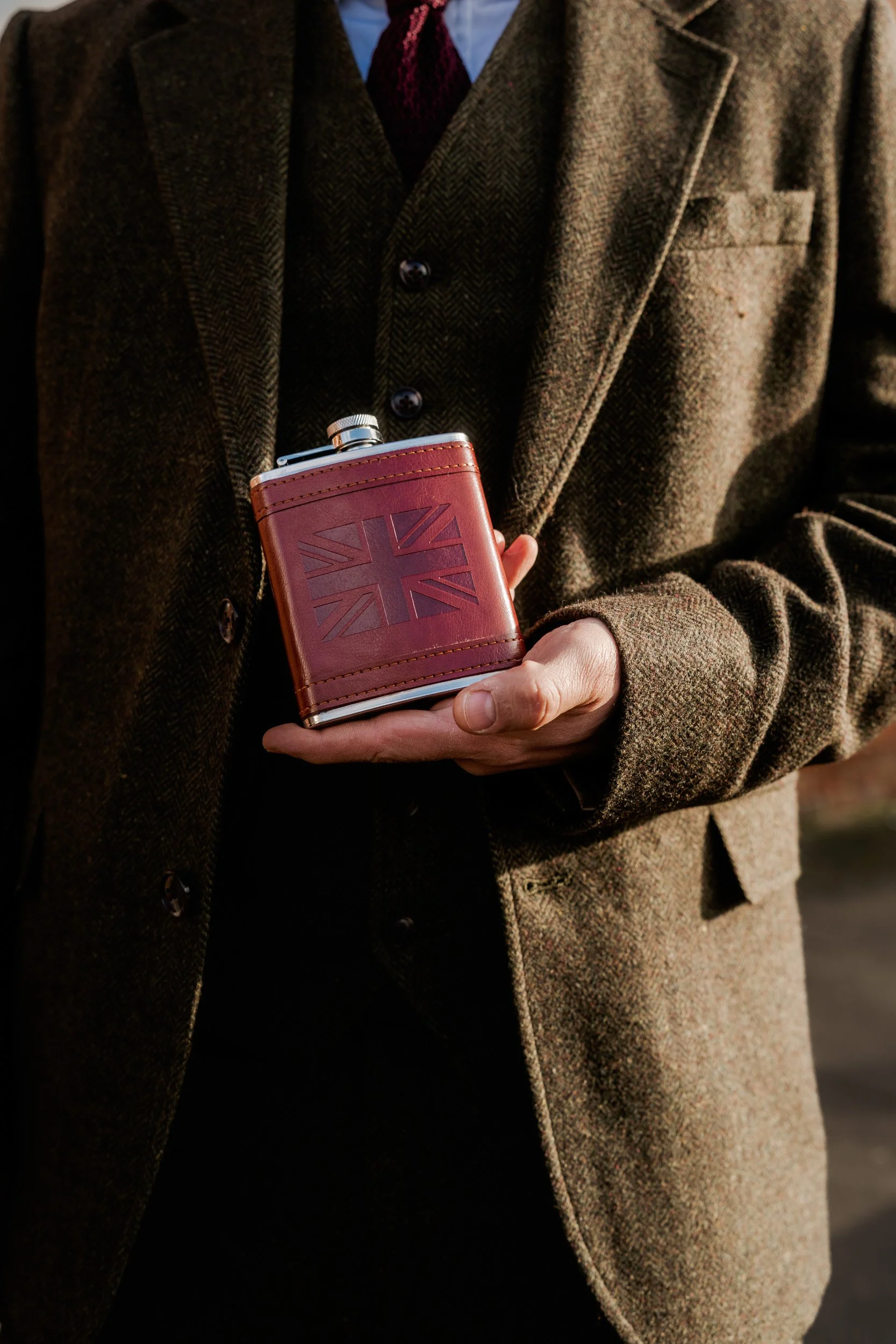 Best Man holding a hip flask outside the Registration Office in Old Beaconsfield Buckinghamshire before their wedding ceremony