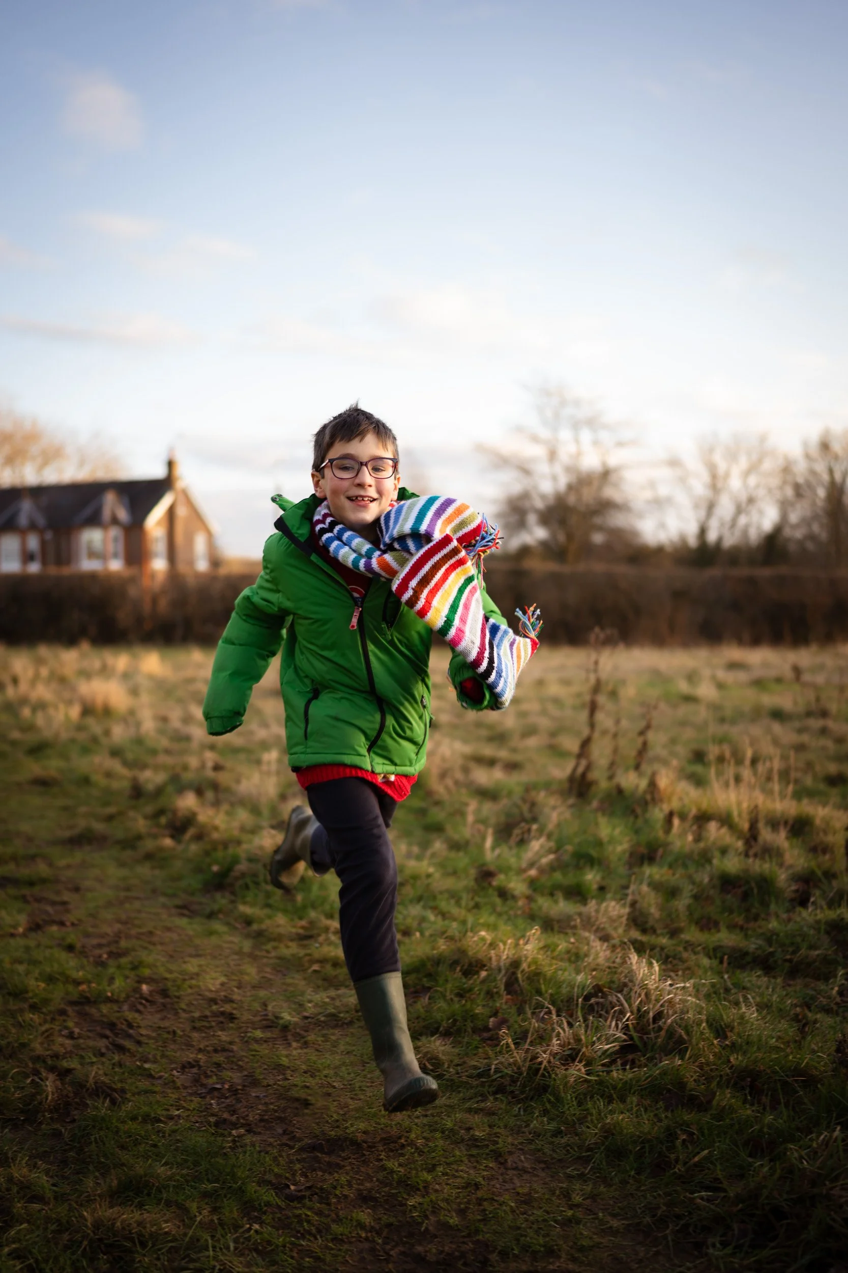 A young boy runs though a field in the golden hour of sunset on a relaxed and natural family photoshoot in Amersham, Buckinghamshire