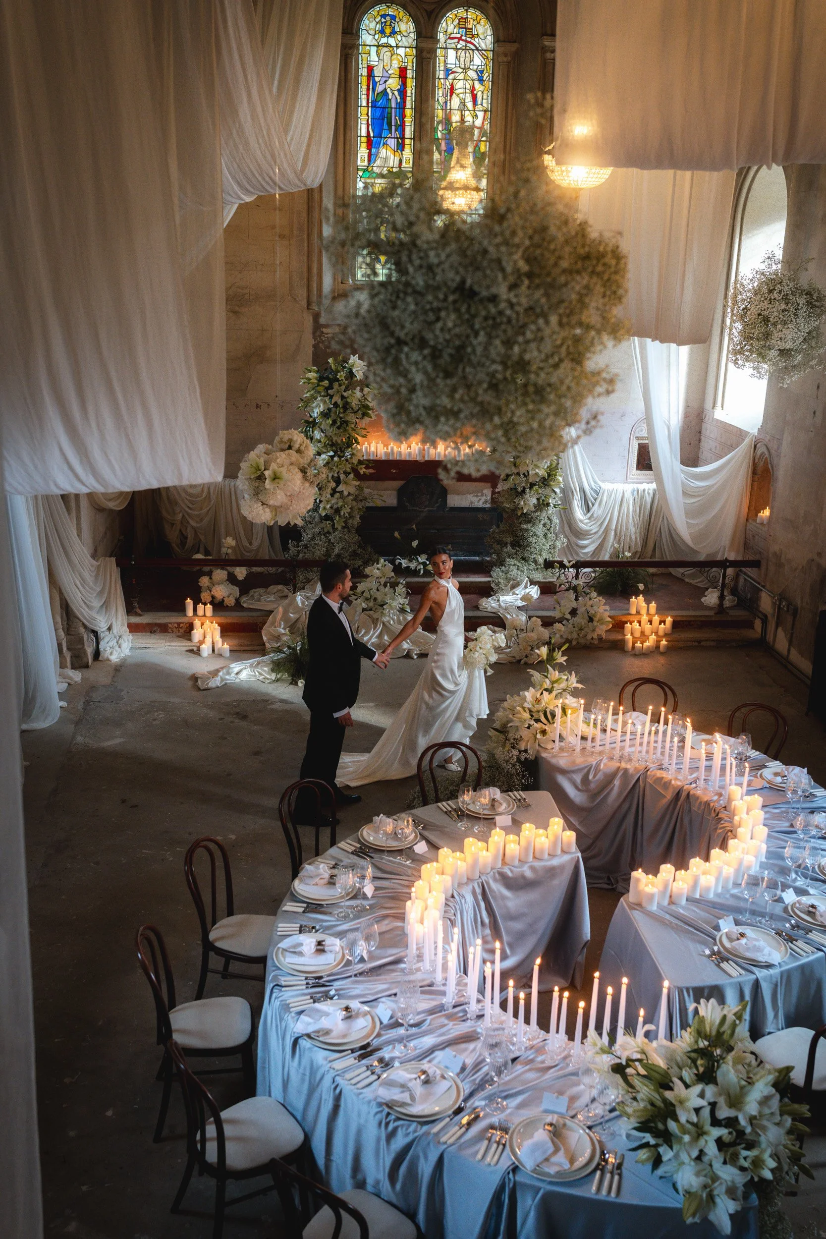 Bride looking back at her groom at their wedding reception in a room with draped fabric inside The Bell Tower at The Elvetham Hotel in Hampshire