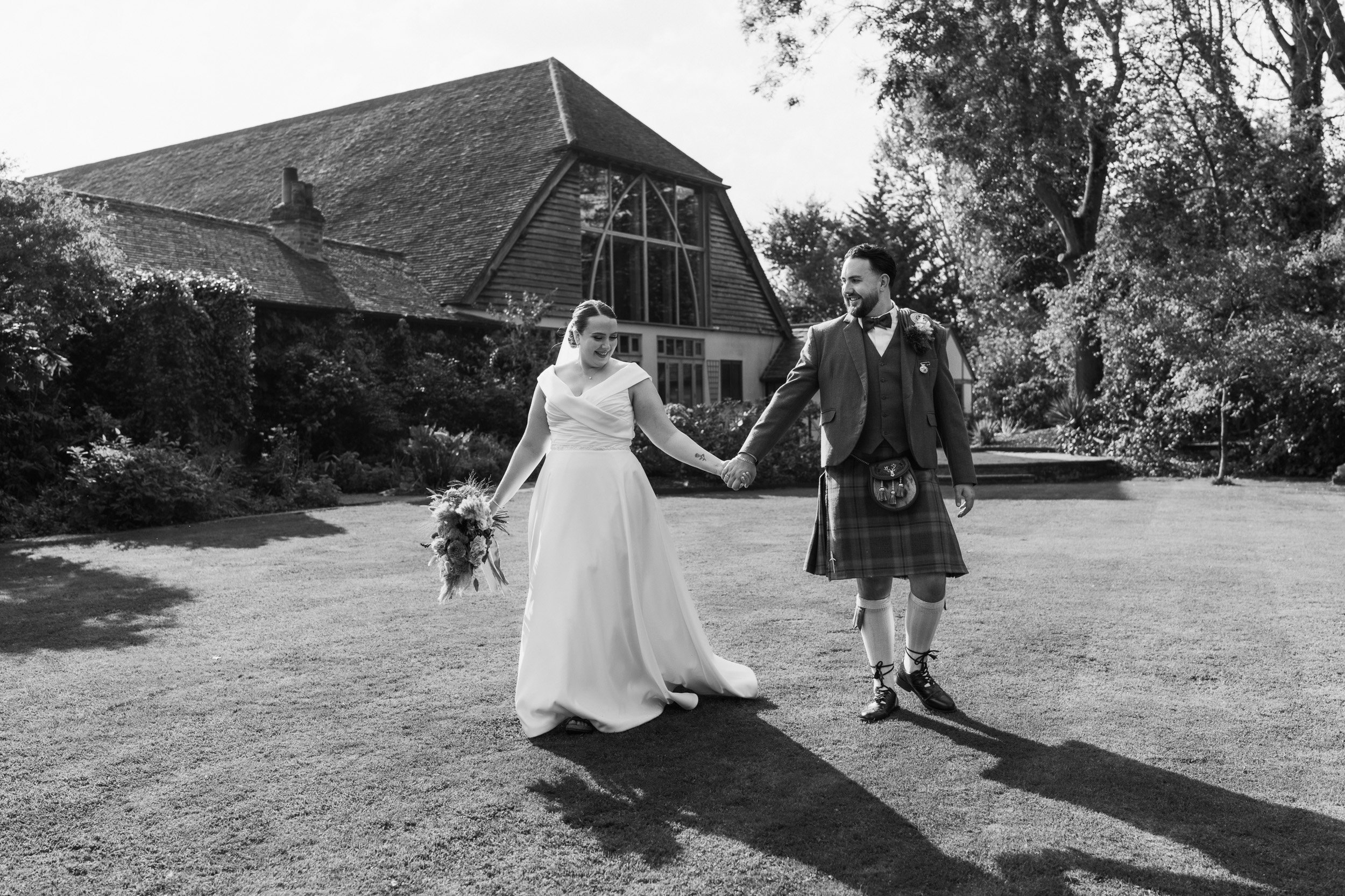 Bride and groom walking through the gardens of Rivervale Barn wedding venue in Hampshire