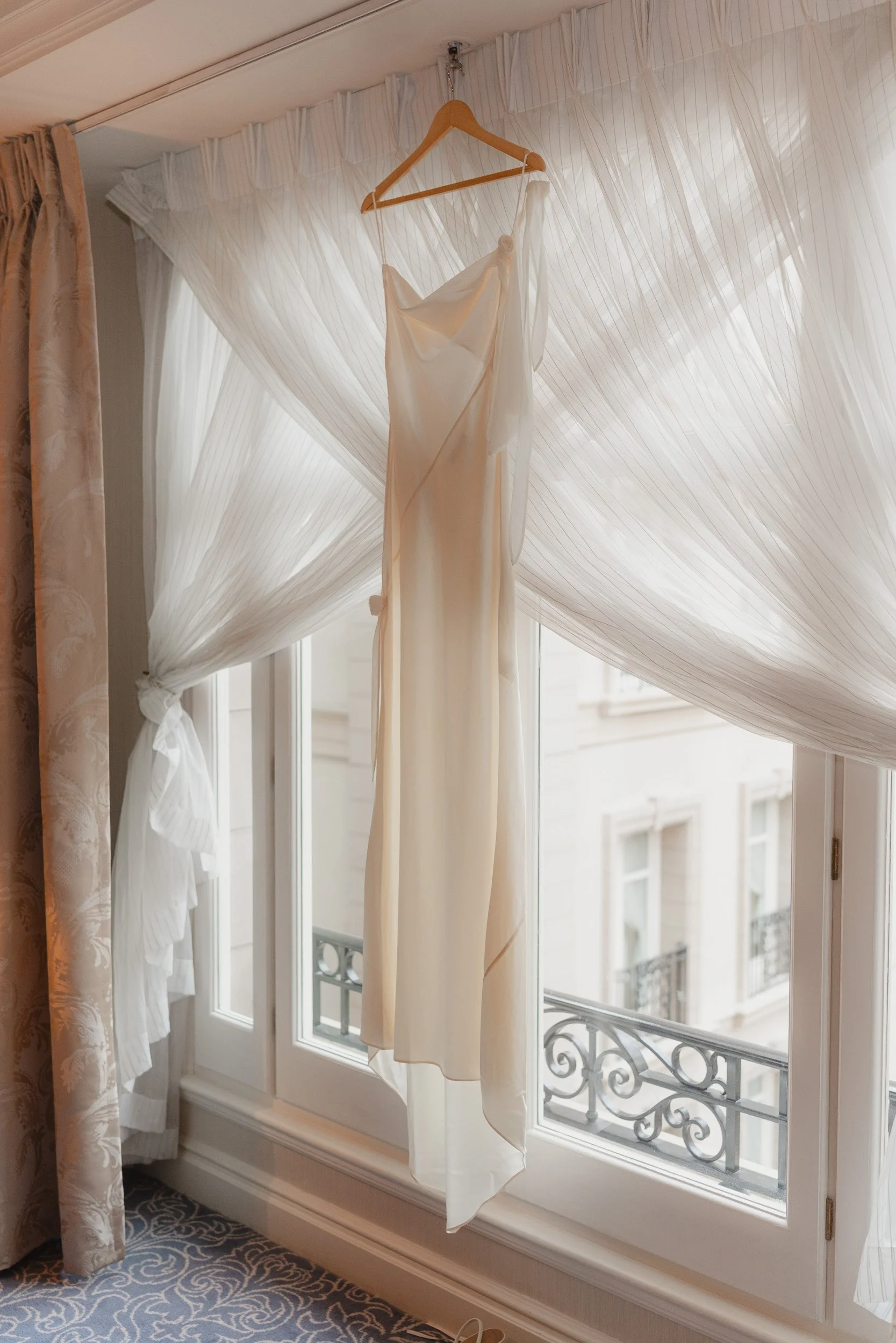 Wedding dress anding in a draped window at The Landmark Hotel in London