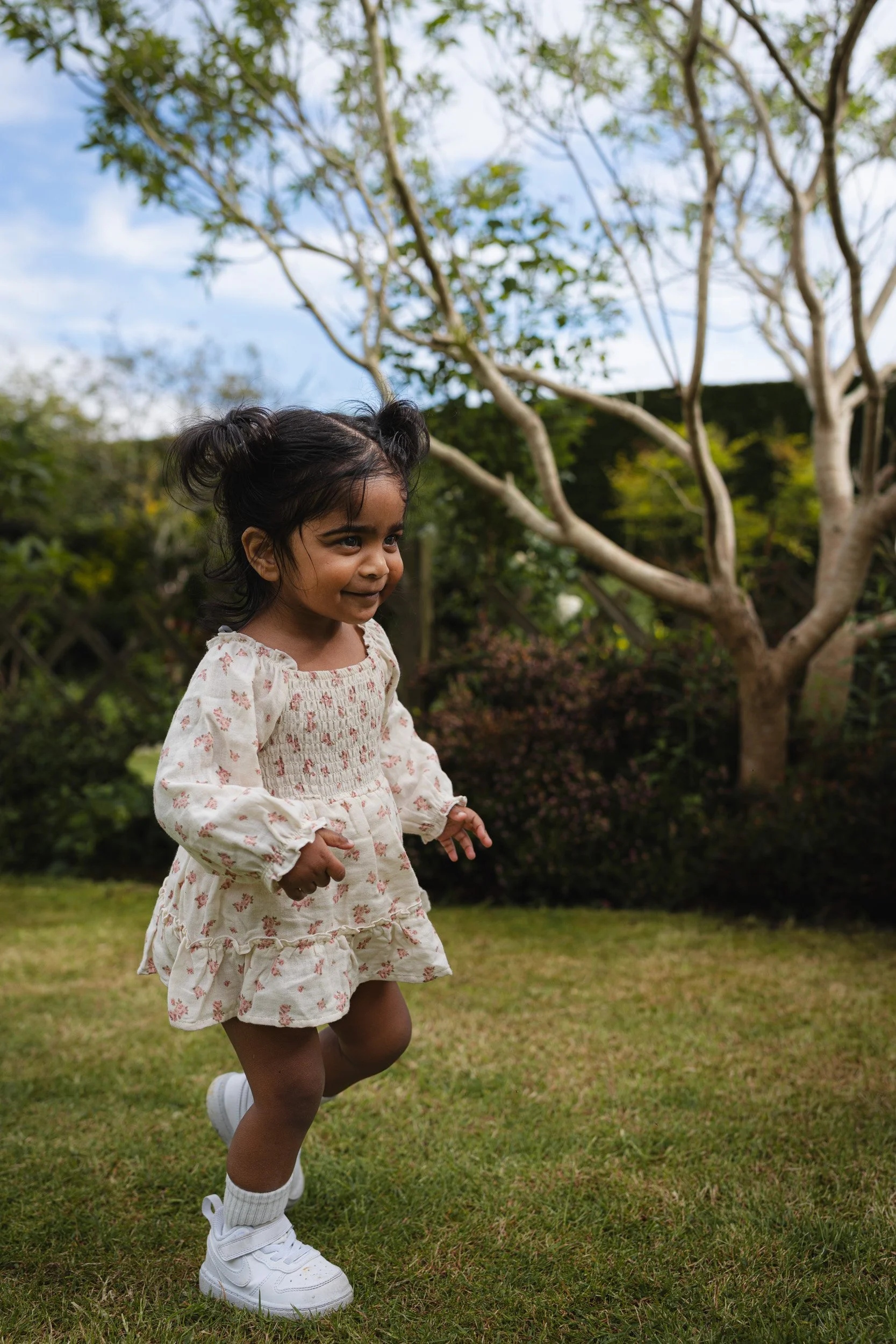 Young child running across the lawn to her parents during a relaxed at-home family photography session in Amersham, Buckinghamshire