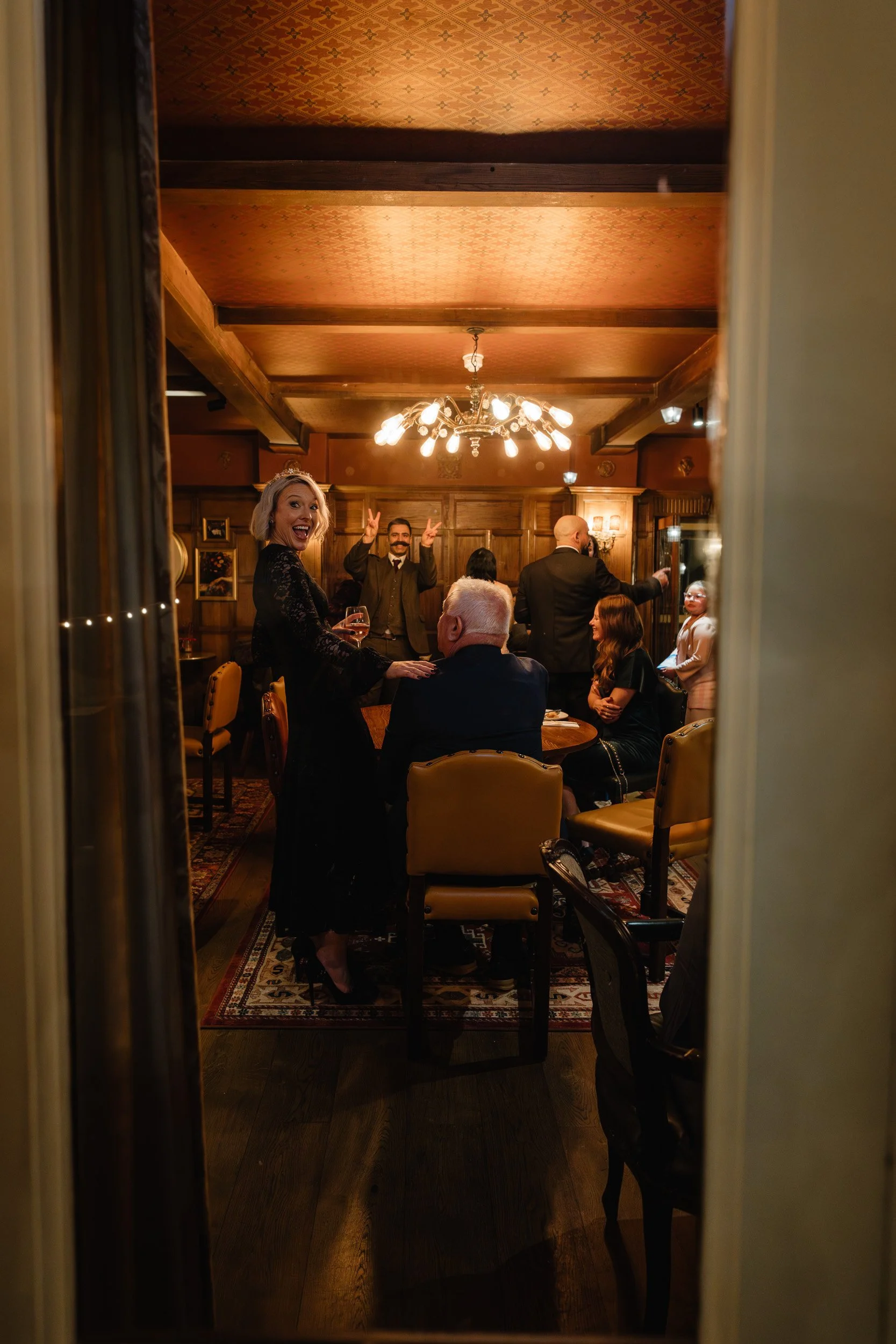 Bride laughs to her photographer whilst she is photographed chatting with guests at The Bedford Arms in Chenies during a wedding reception