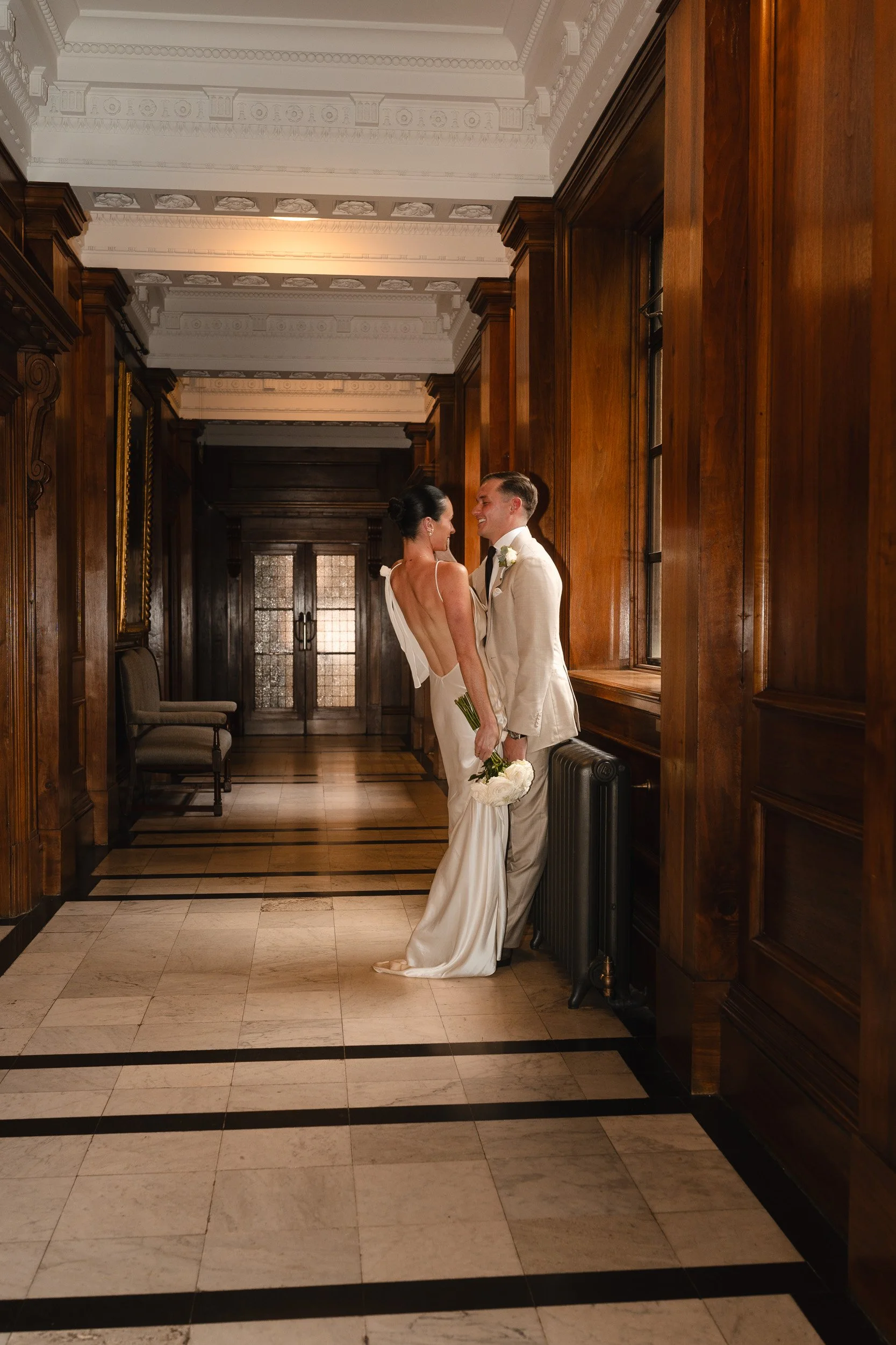 Groom pulling his bride in for a kiss in the hallways of Marylebone Town Hall Registry Office in London  