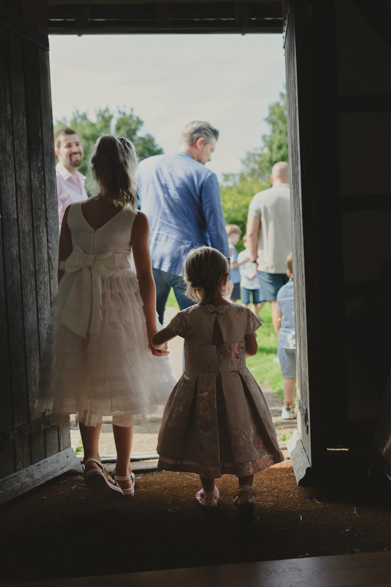 Two young girls walking hand in hand into a family christening celebration in Amersham, Buckinghamshire